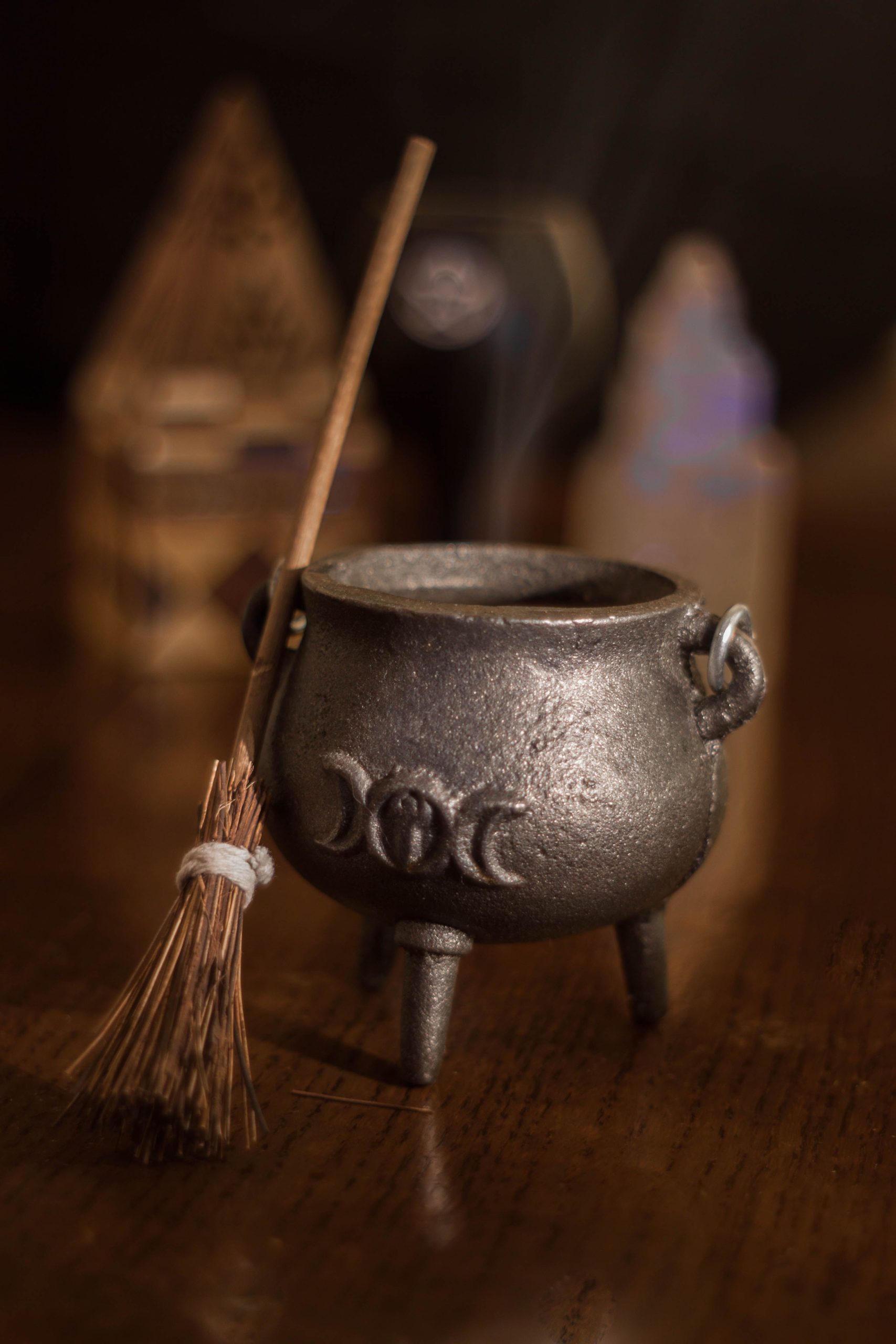 A mystical miniature cauldron with a broomstick, evoking themes of witchcraft and magic.