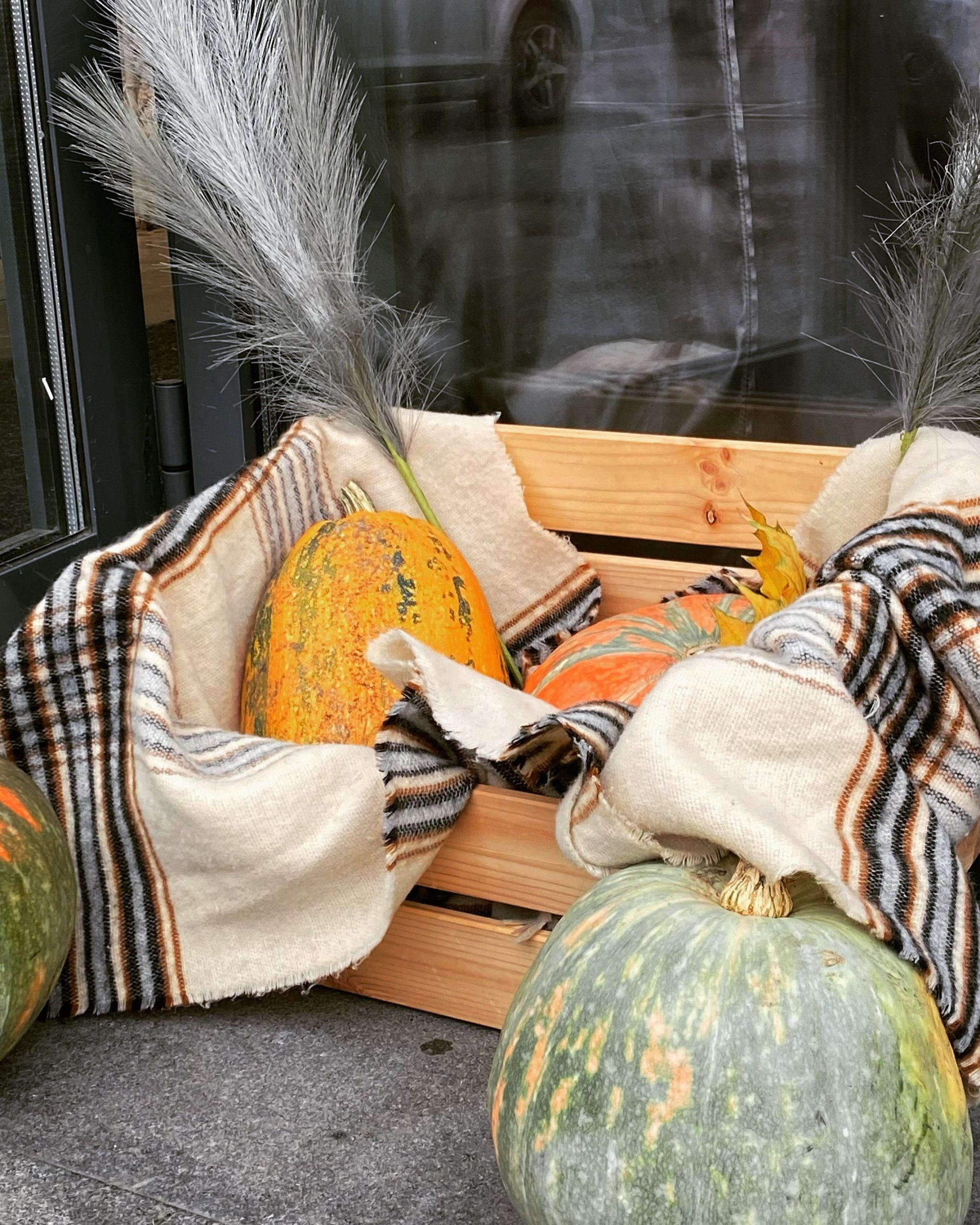 A rustic autumn pumpkin display with a cozy plaid blanket, perfect for fall decoration.