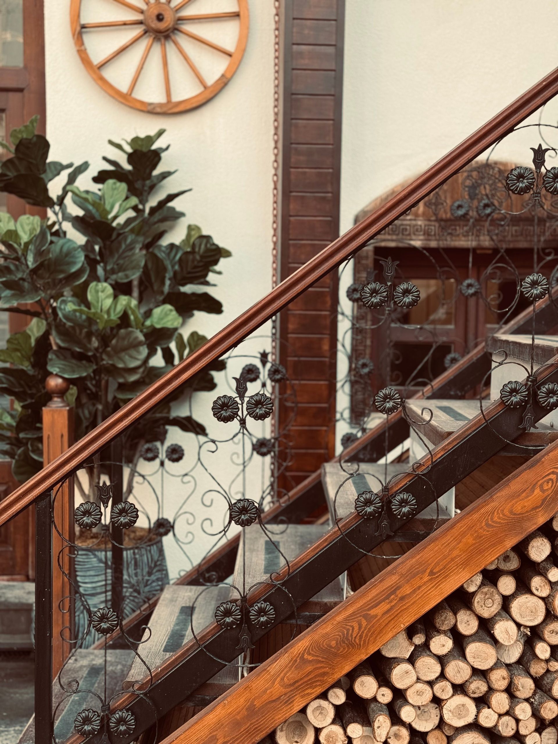 A rustic indoor staircase with decorative iron railing and wooden accents, featuring plant decor.