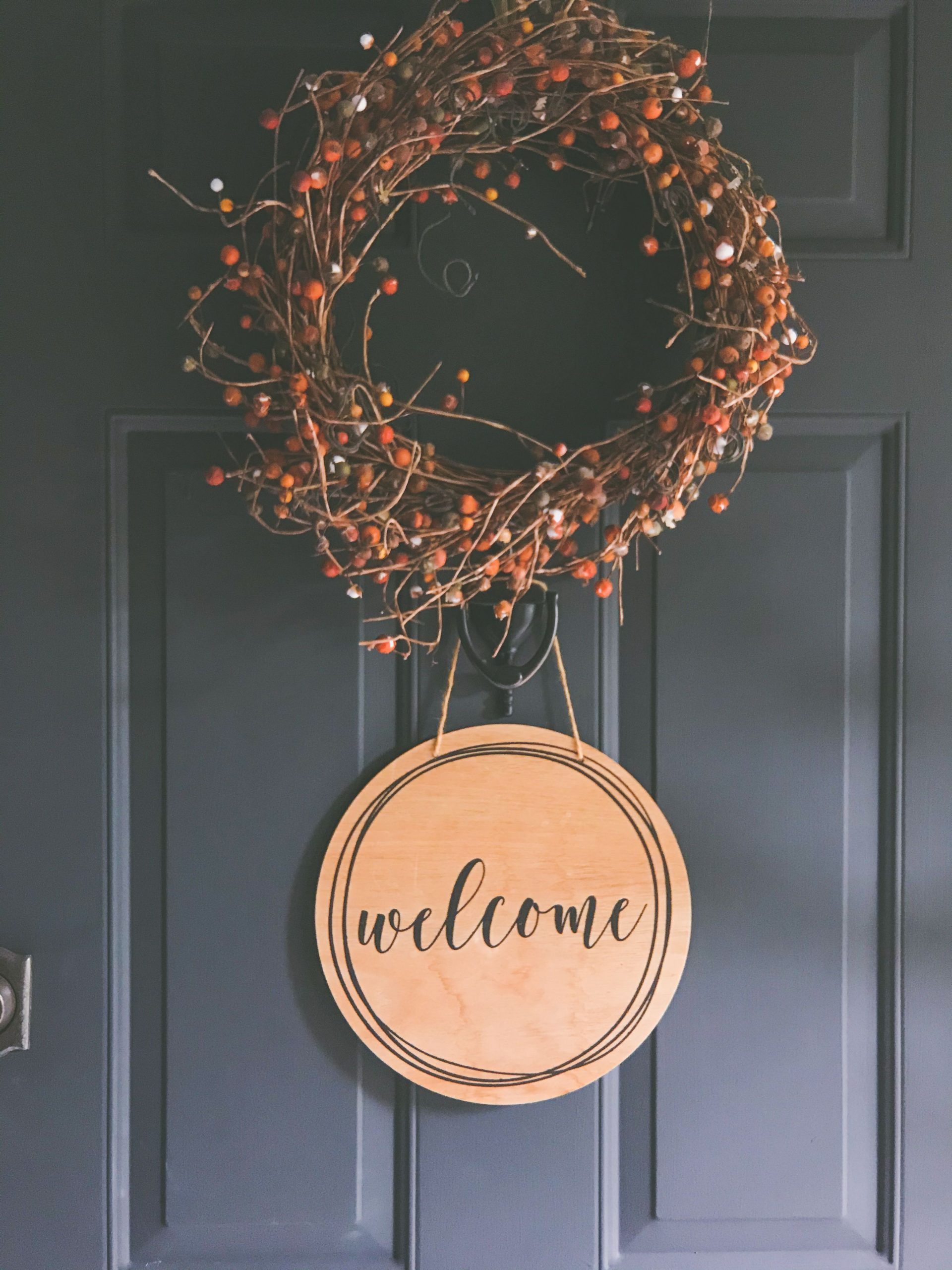 A rustic wreath with a welcome sign on a dark door, creating a warm invitation.