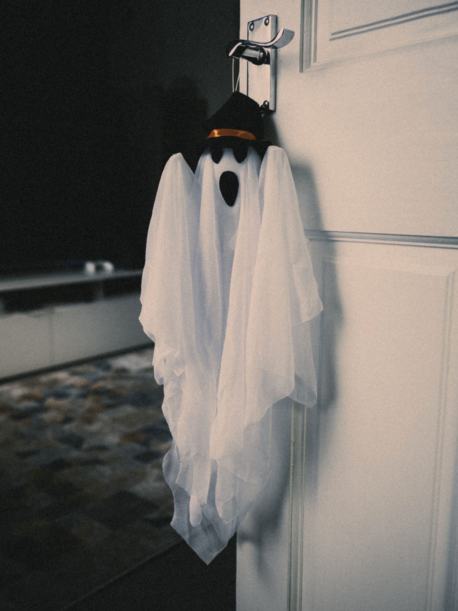 A spooky ghost decoration with a hat hanging on a door, perfect for Halloween ambiance.