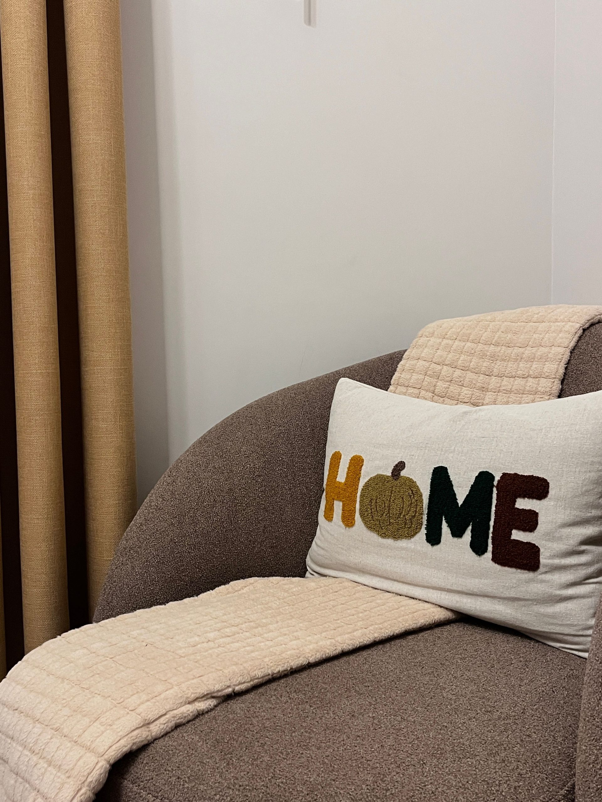 A stylish chair with a cozy autumn-themed pillow in a modern living room setting.