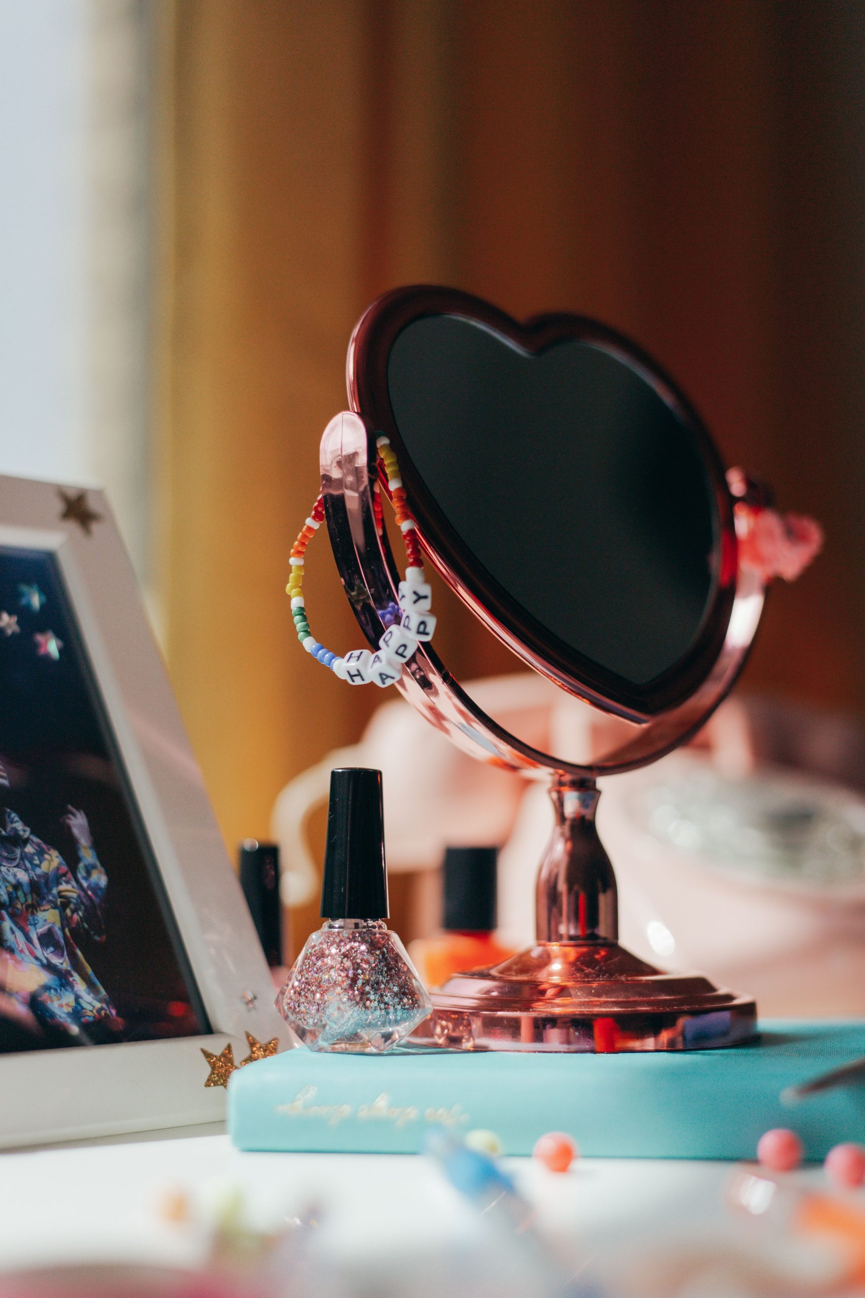 A stylish vanity setup featuring a heart-shaped mirror, nail polish, and colorful beads.