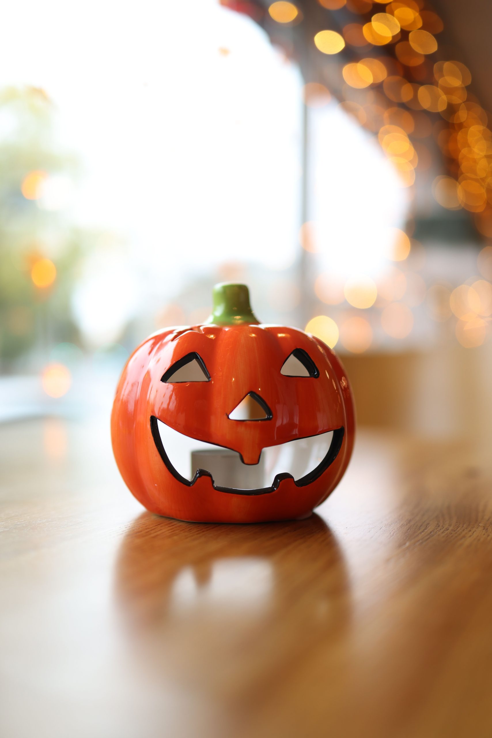 A vibrant ceramic jack-o'-lantern on a windowsill, capturing the festive autumn spirit indoors.