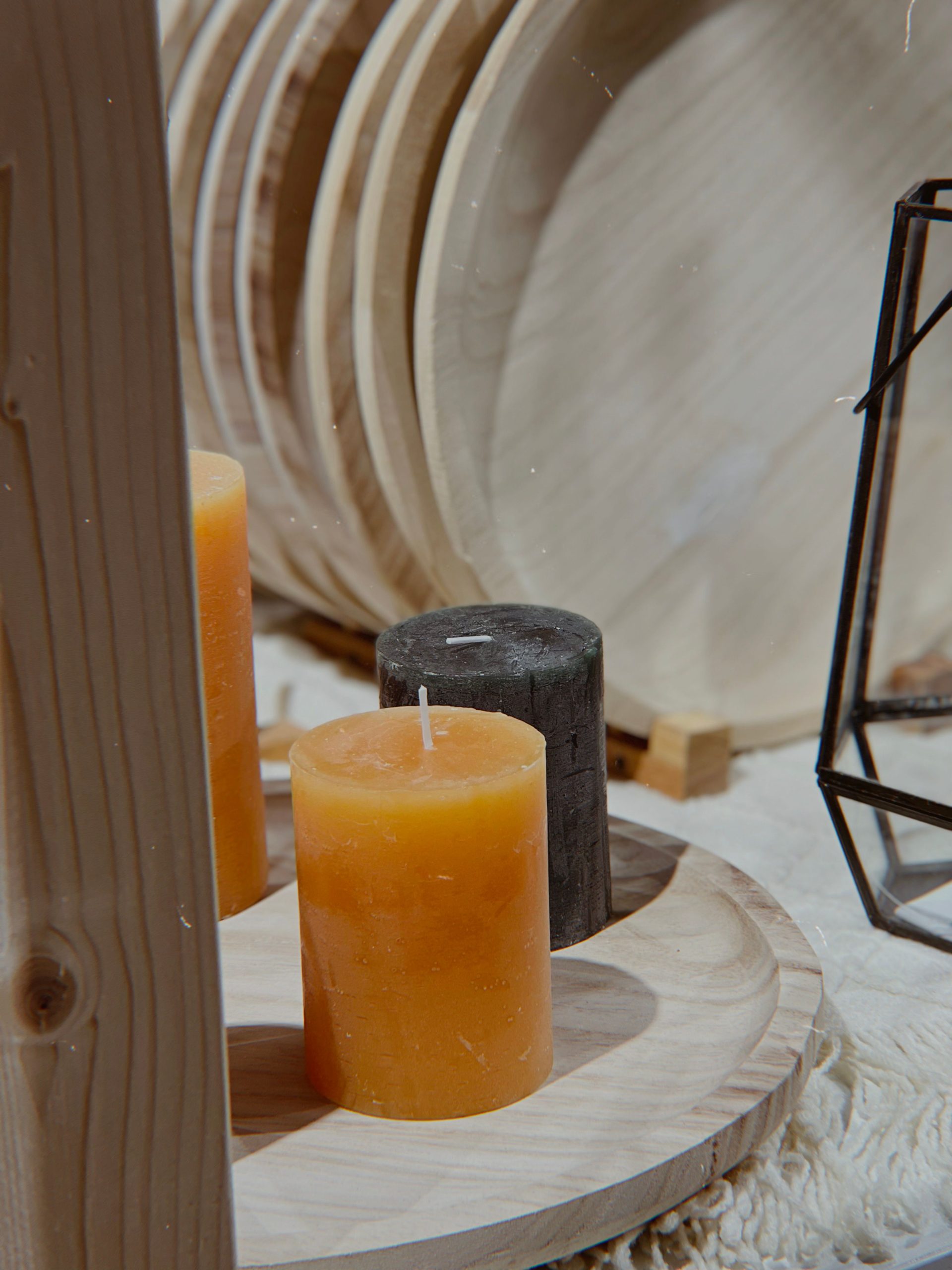 A warm and inviting setup featuring candles on a wooden tray, surrounded by rustic decor.