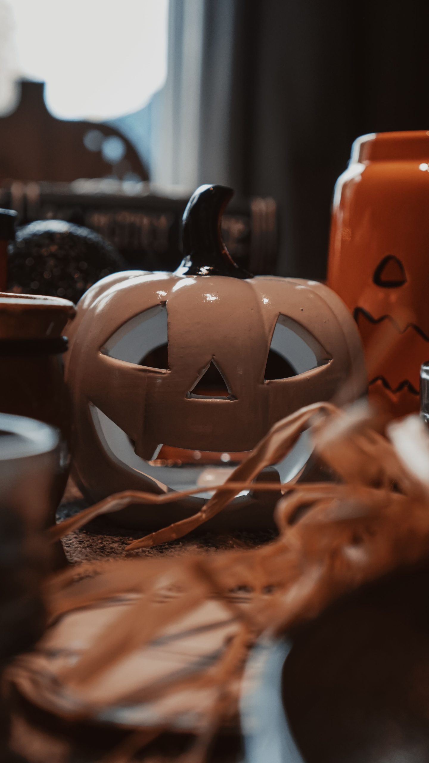 A warm, artistic portrayal of Halloween decor featuring a ceramic jack-o'-lantern with subtle lighting.