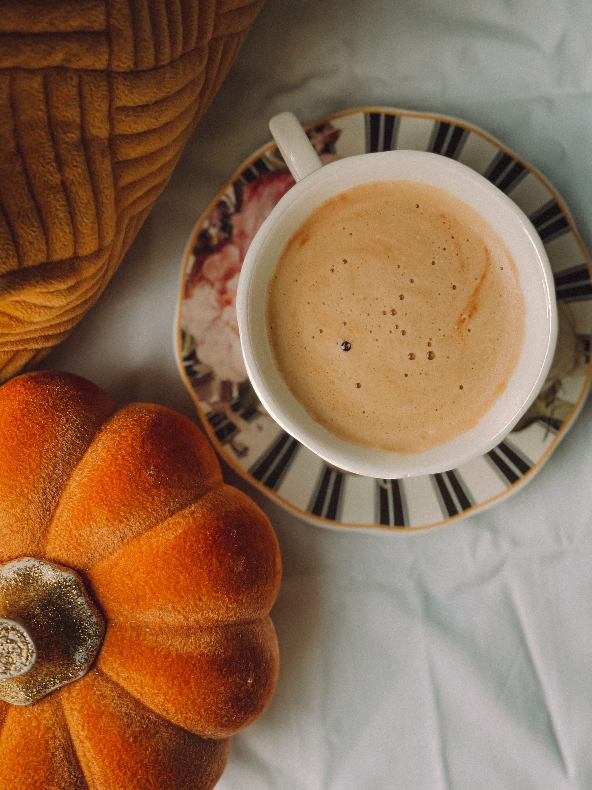 A warm cup of coffee with a pumpkin decoration, perfect for fall mornings.