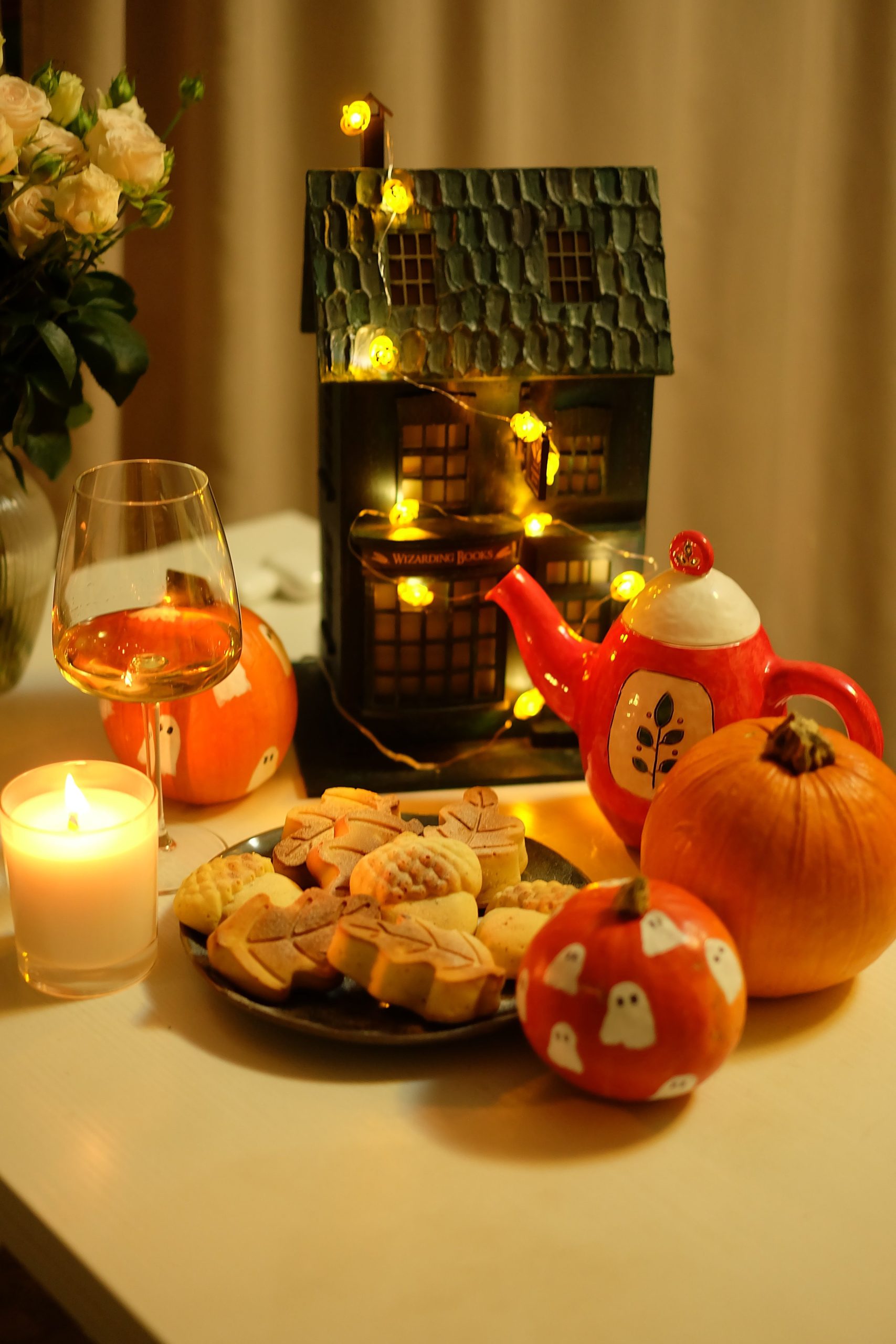 A warm Halloween table setting featuring pumpkins, cookies, and festive decorations for a cozy celebration.