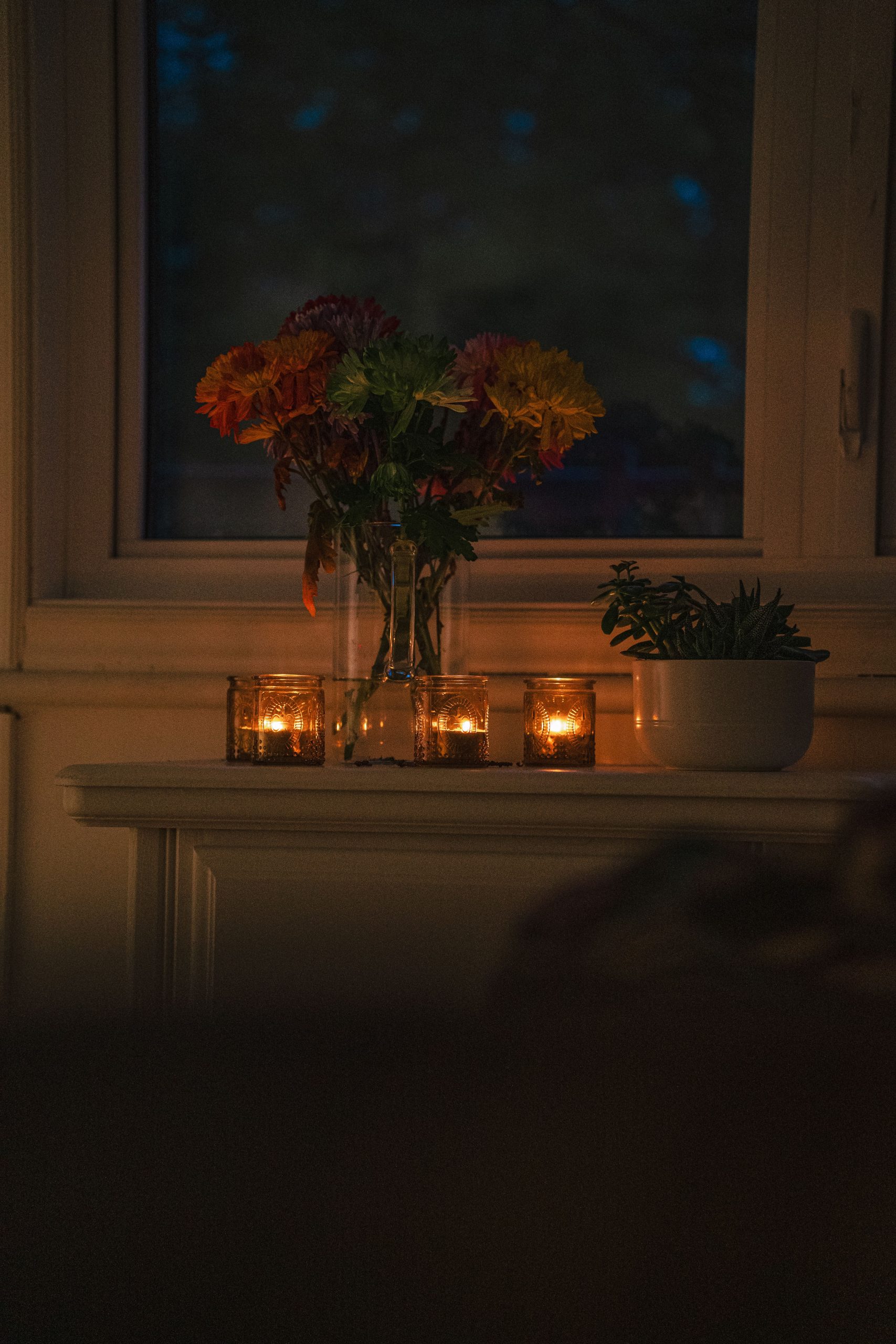 A warm, intimate setting with candles and flowers by a window, creating a cozy evening ambiance.