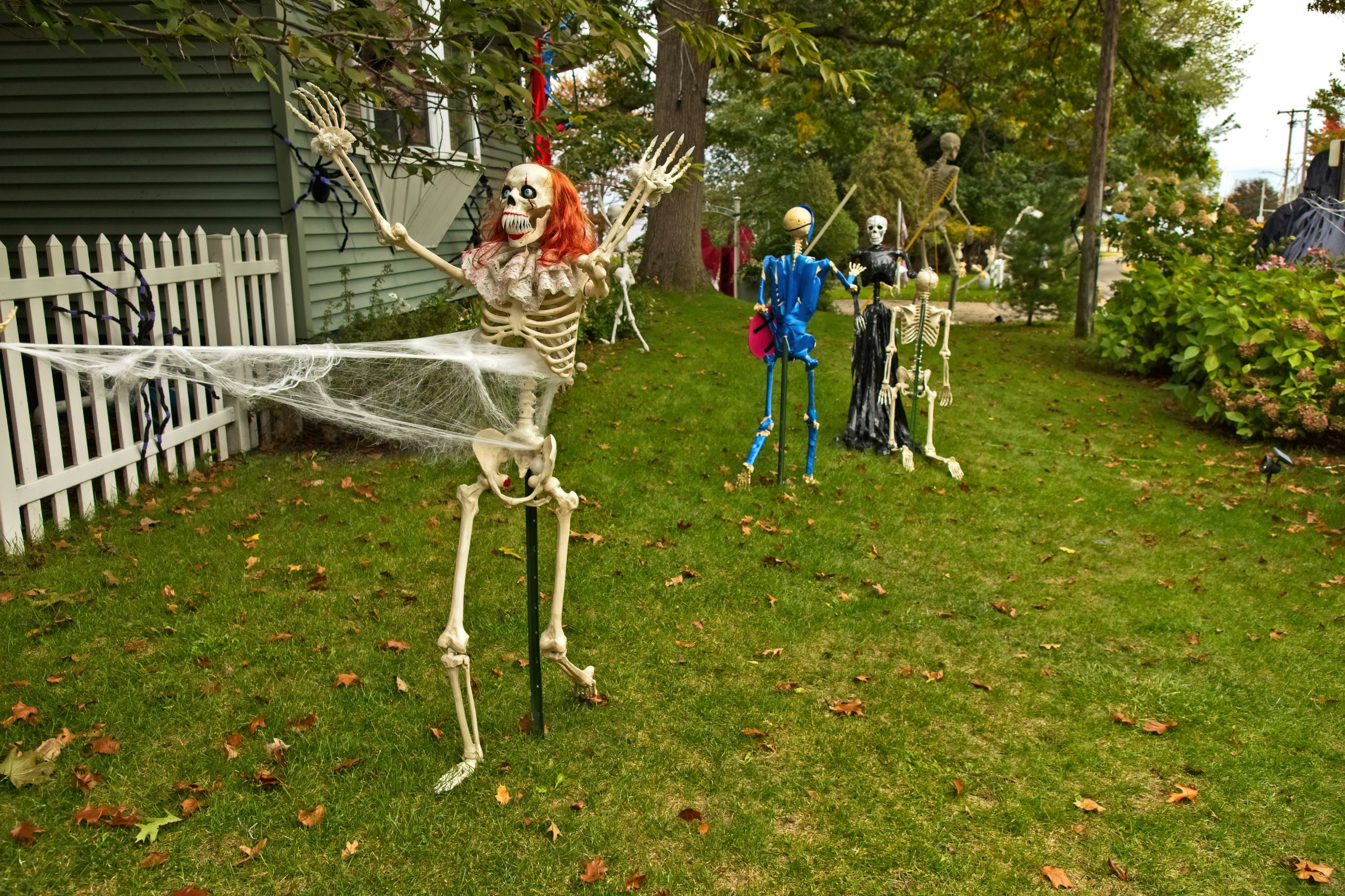 a yard decorated for halloween with skeletons and spider webs
