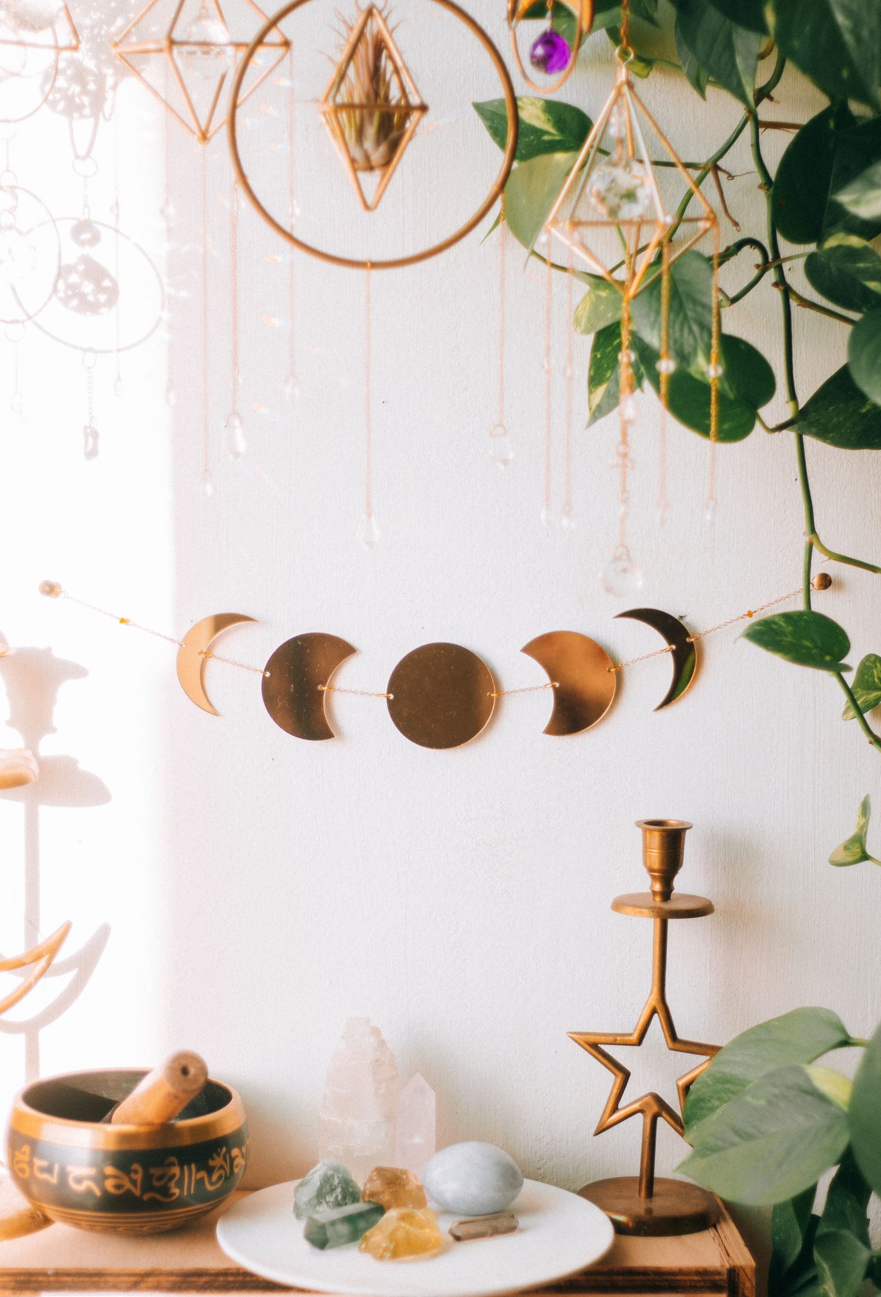 Artistic bohemian interior with moon phase decor, crystals, and lush plants.