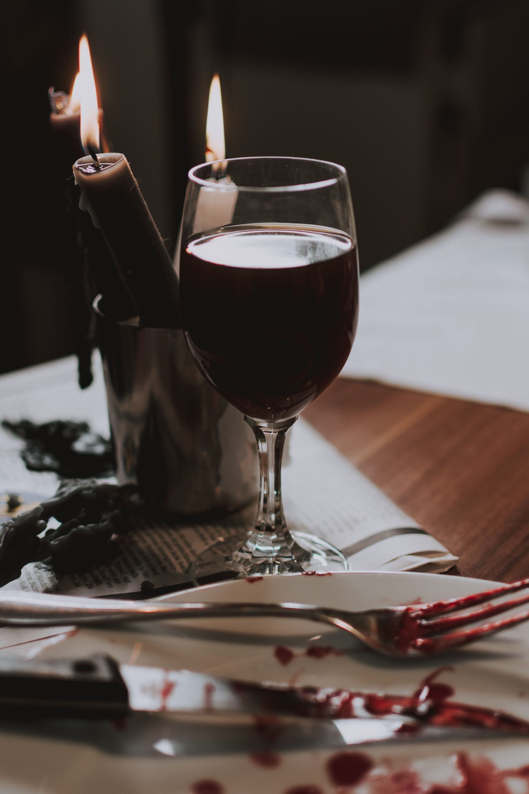 Atmospheric still life featuring a red wine glass, candlelight, and table setting.