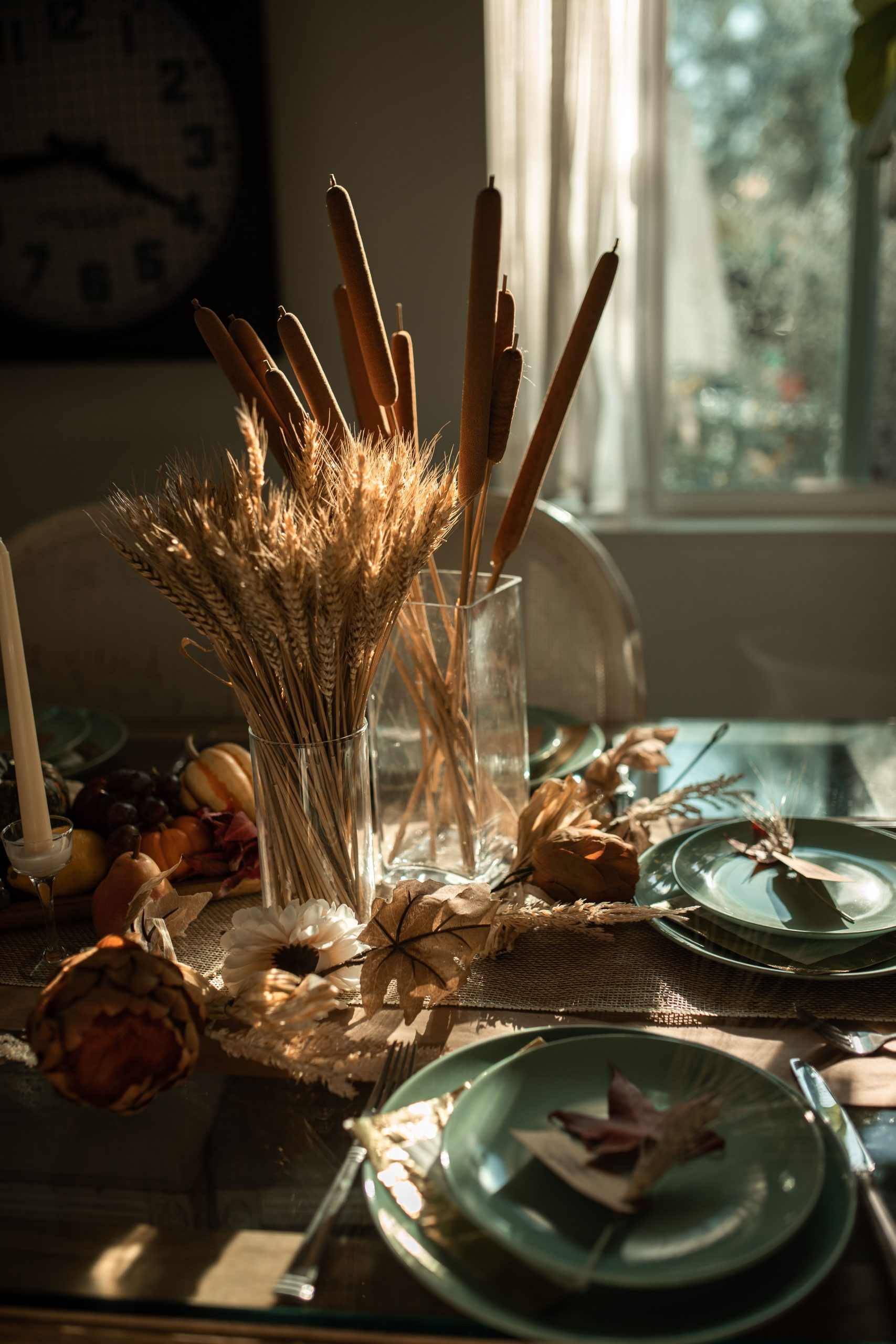 Autumn-themed dining table with centerpiece featuring wheat and cattails, capturing warm golden light.