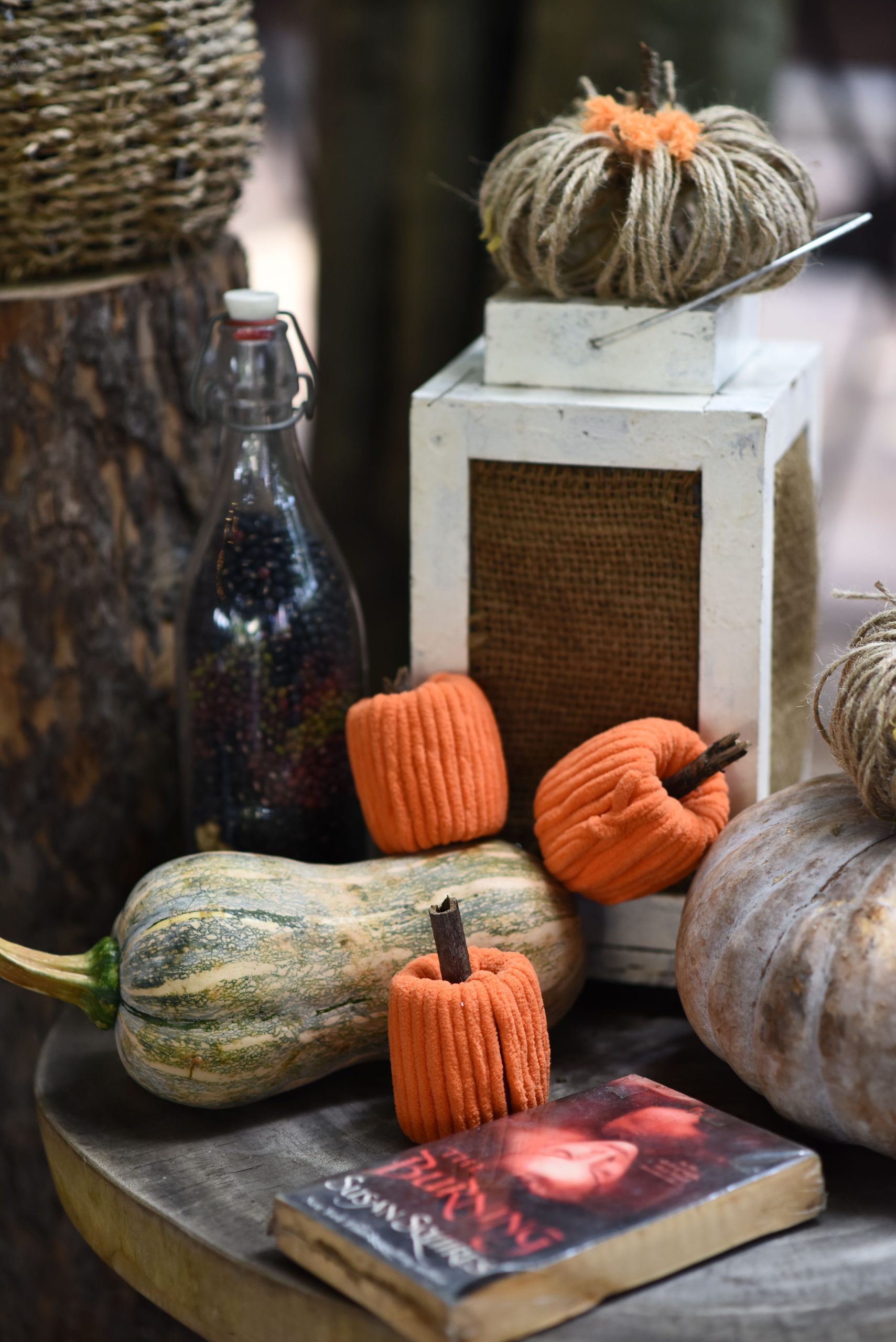 Autumn-themed still life featuring pumpkins, lantern, and a book, perfect for fall ambiance.