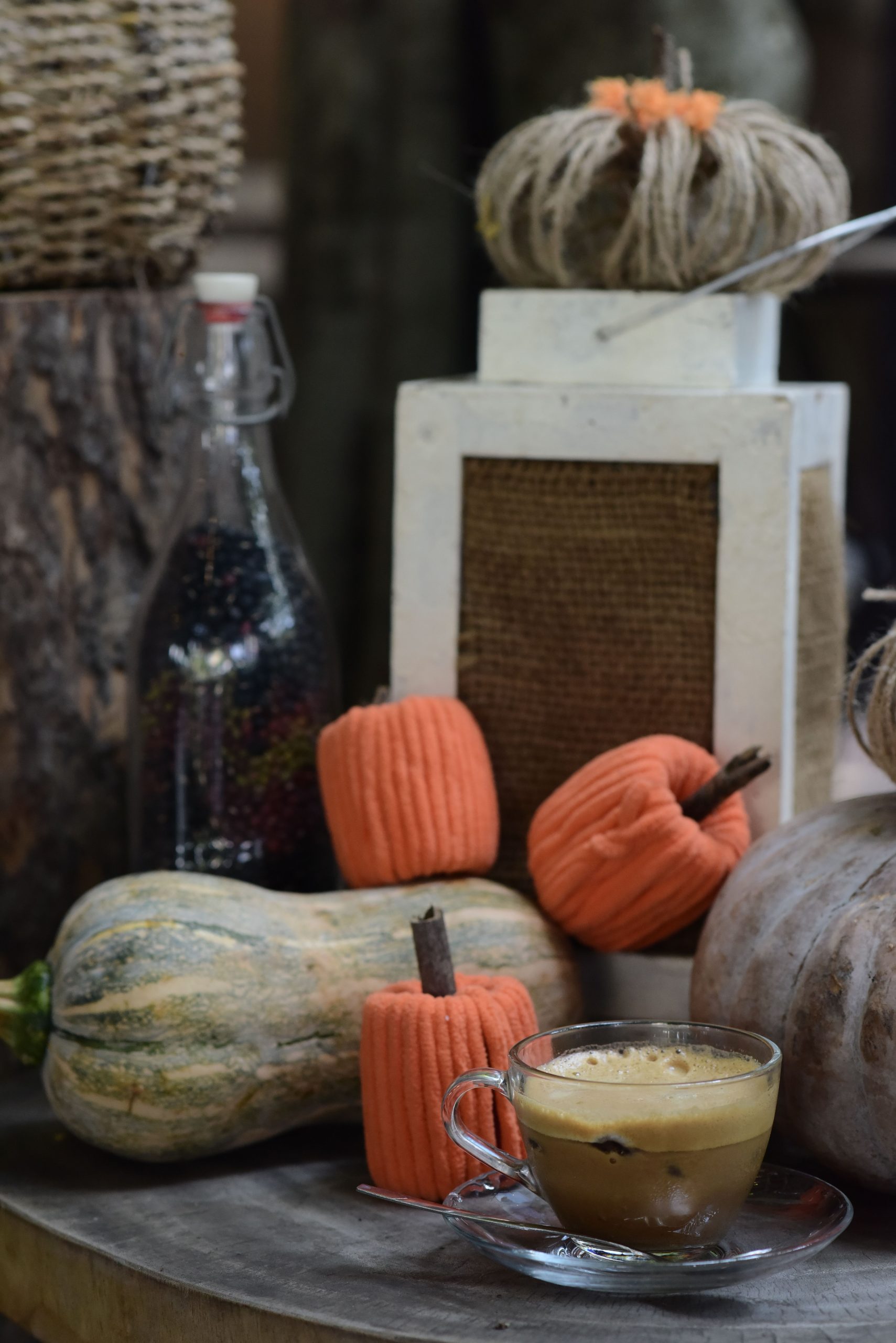 Autumn-themed still life with pumpkins, a cup of coffee, and rustic decorations.