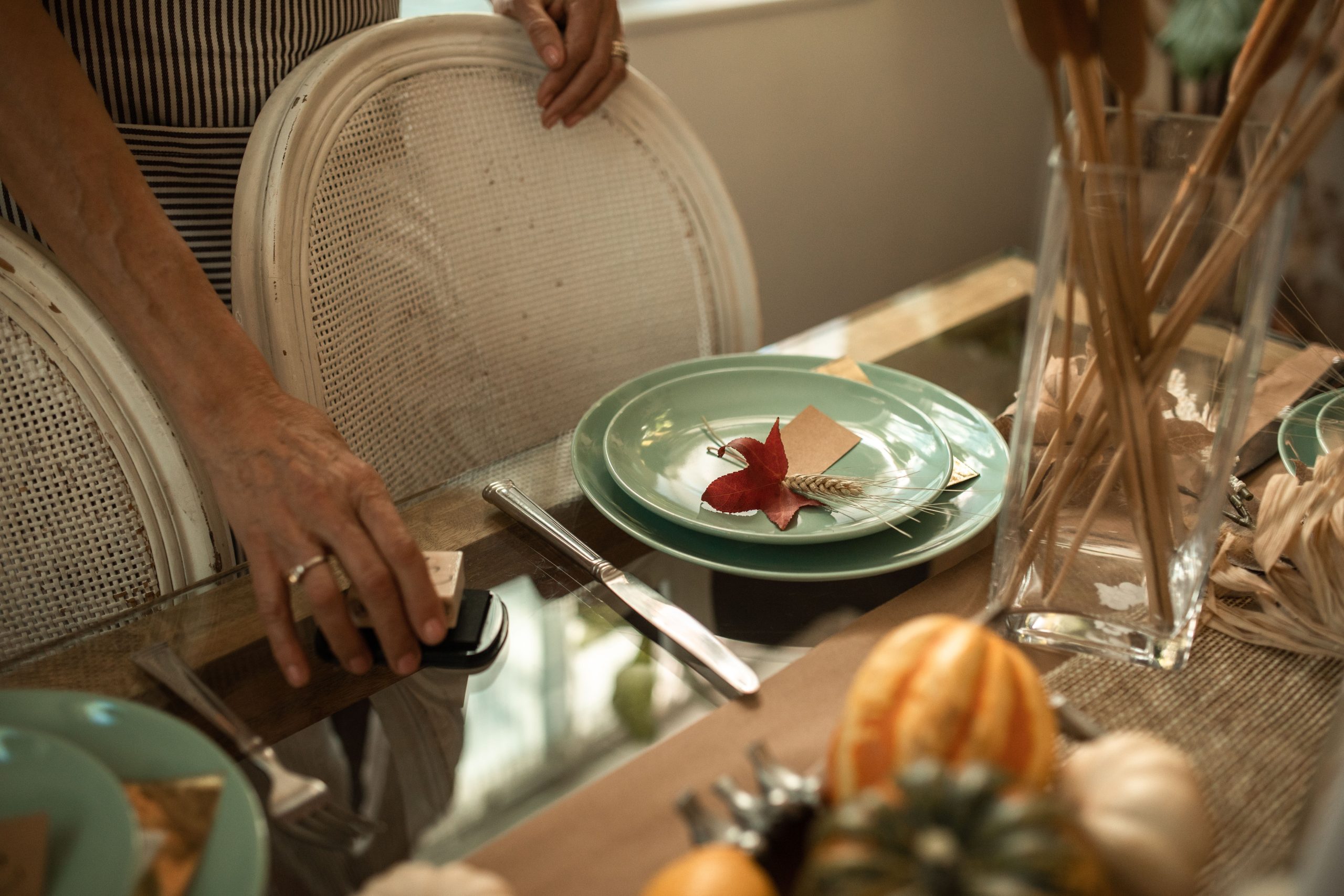 Beautifully arranged Thanksgiving table setting with fall leaves and pumpkins.