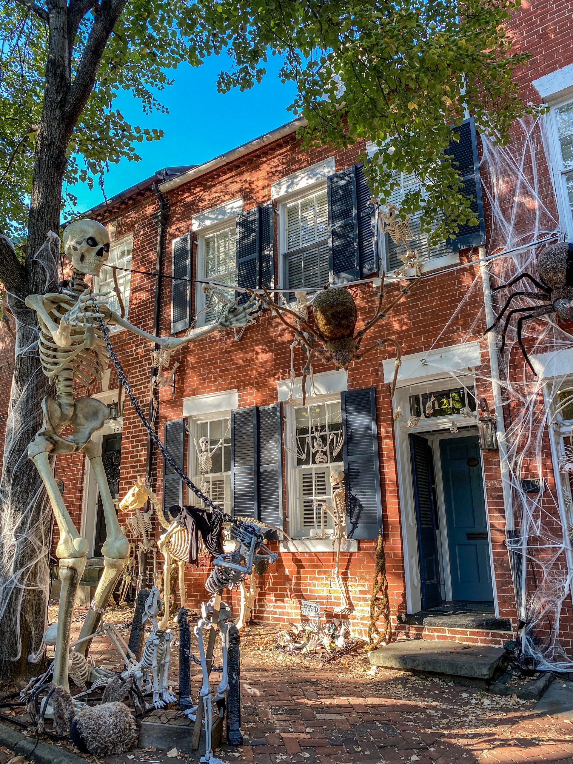 Brick house adorned with Halloween decorations including skeletons and spiderwebs during fall.