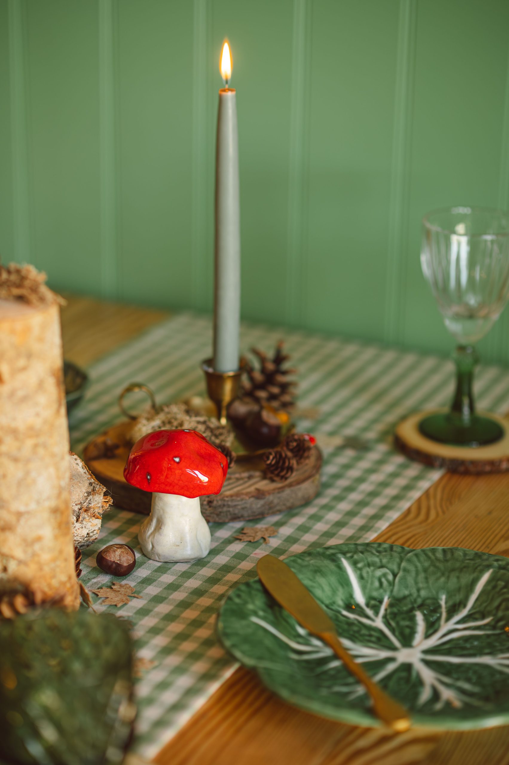Charming autumn table setting with candle, mushroom decor, and woodland elements.