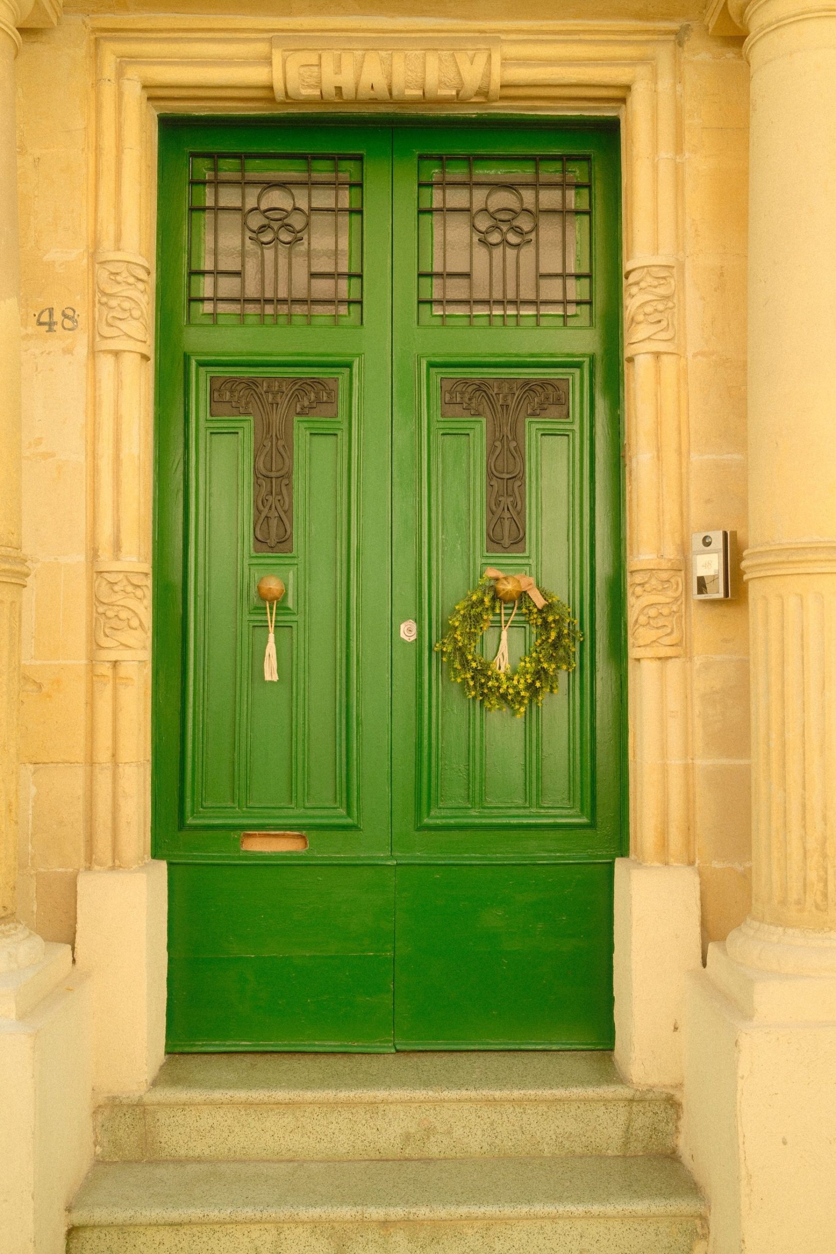 Charming green door with decorative wreath and architectural details in natural light.