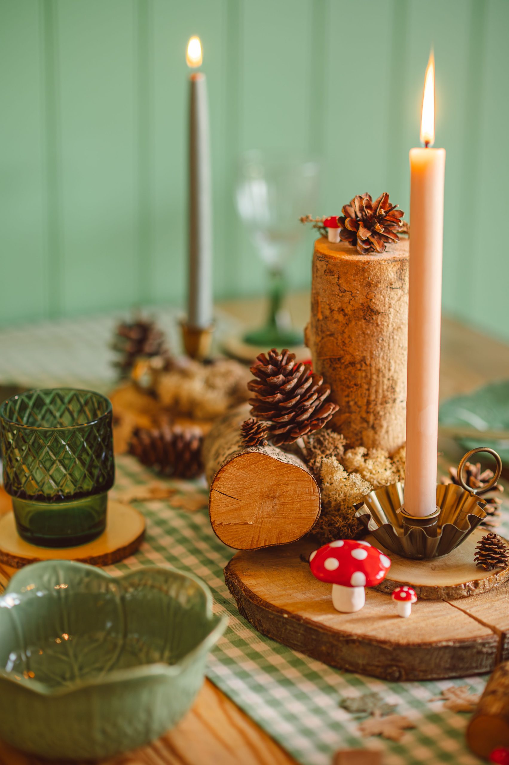 Cozy autumn decor with pinecones, candles, and moss for a warm, rustic table setting.