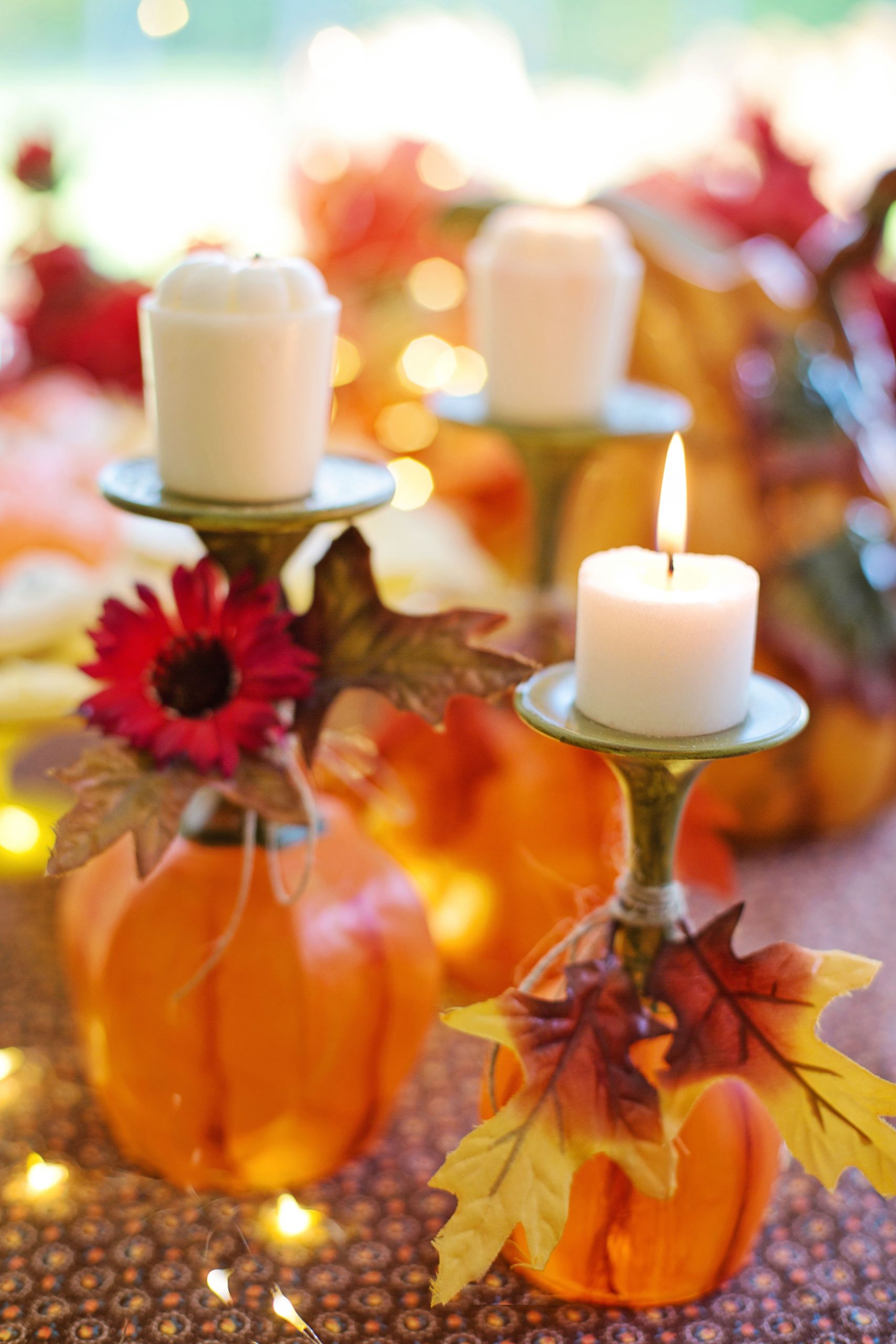 Cozy autumn table decor with pumpkins, candles, and leaves, perfect for seasonal gatherings.