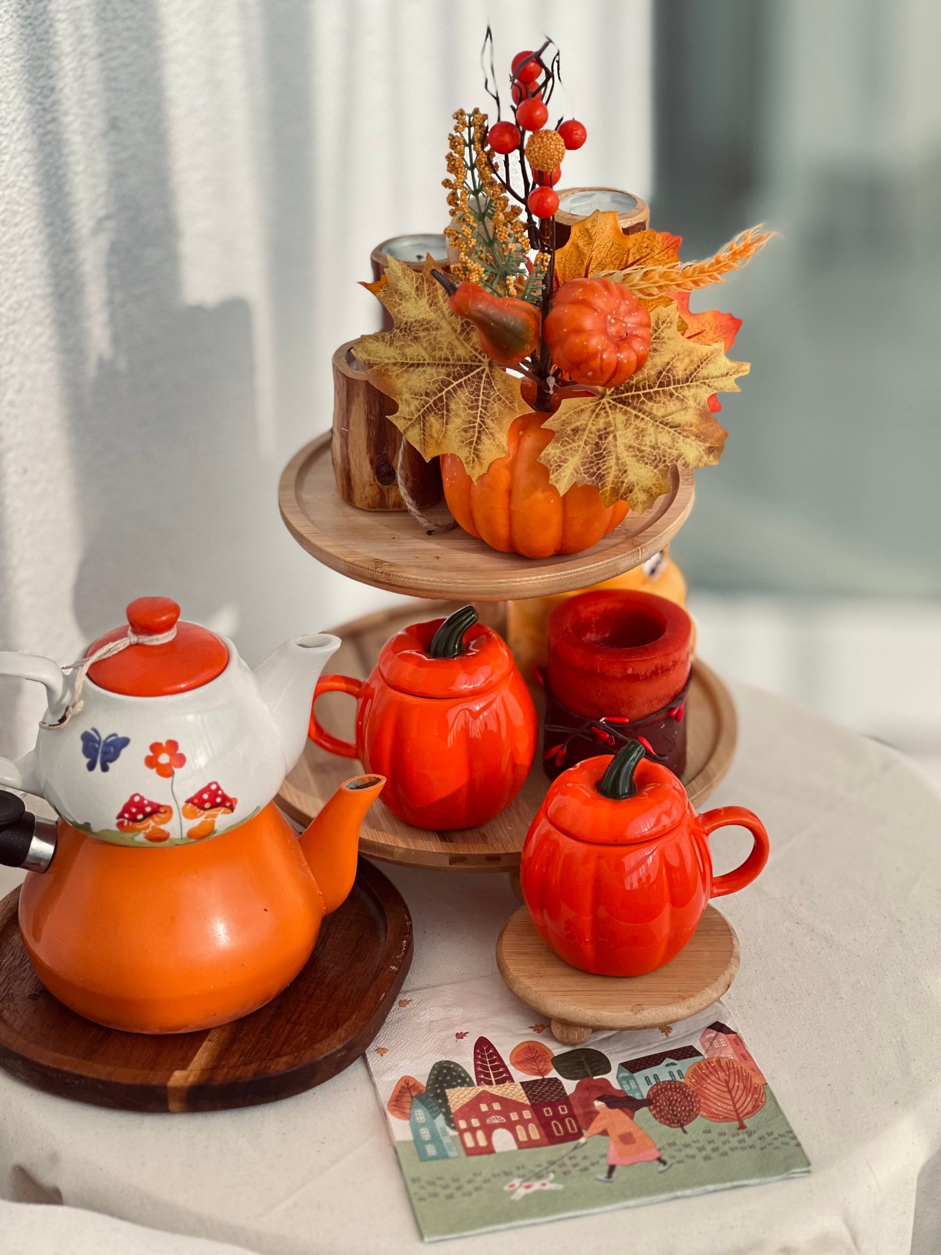Cozy autumn tea setup with pumpkin mugs and fall leaves.