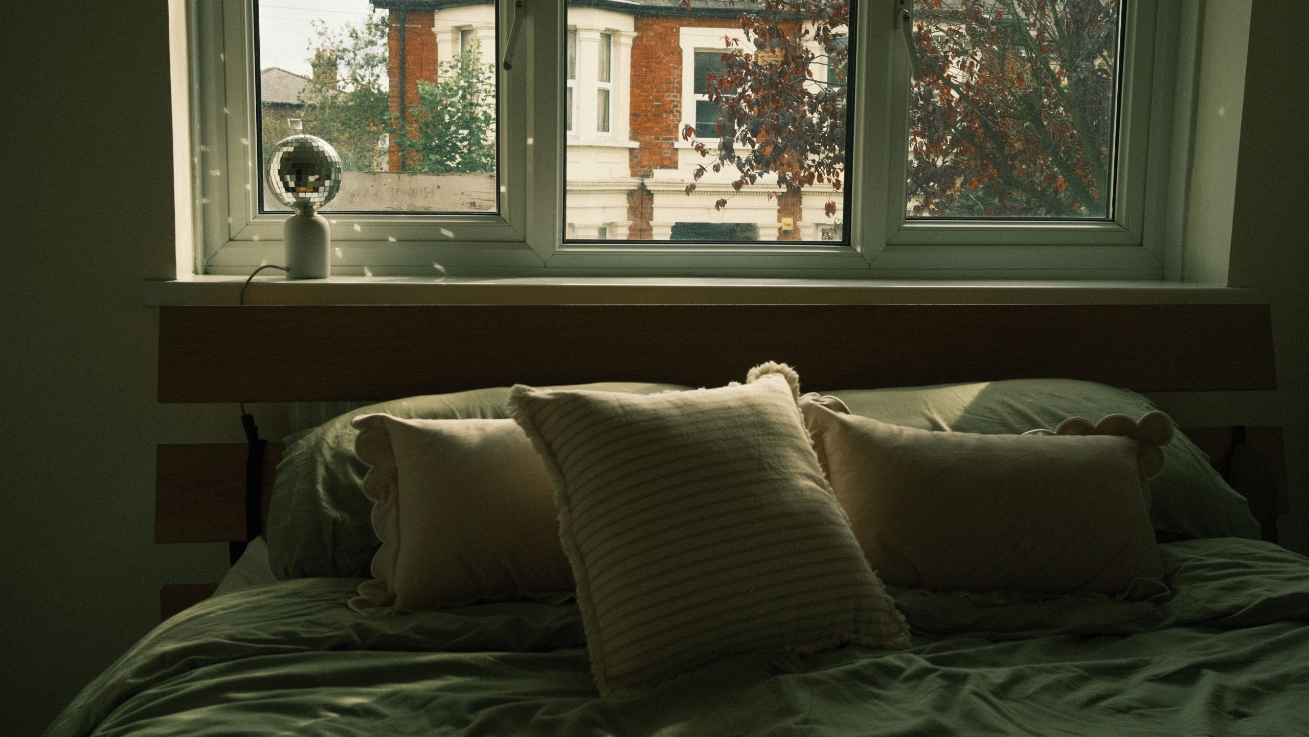 Cozy bedroom with soft pillows and a window view in autumn. Inviting atmosphere.