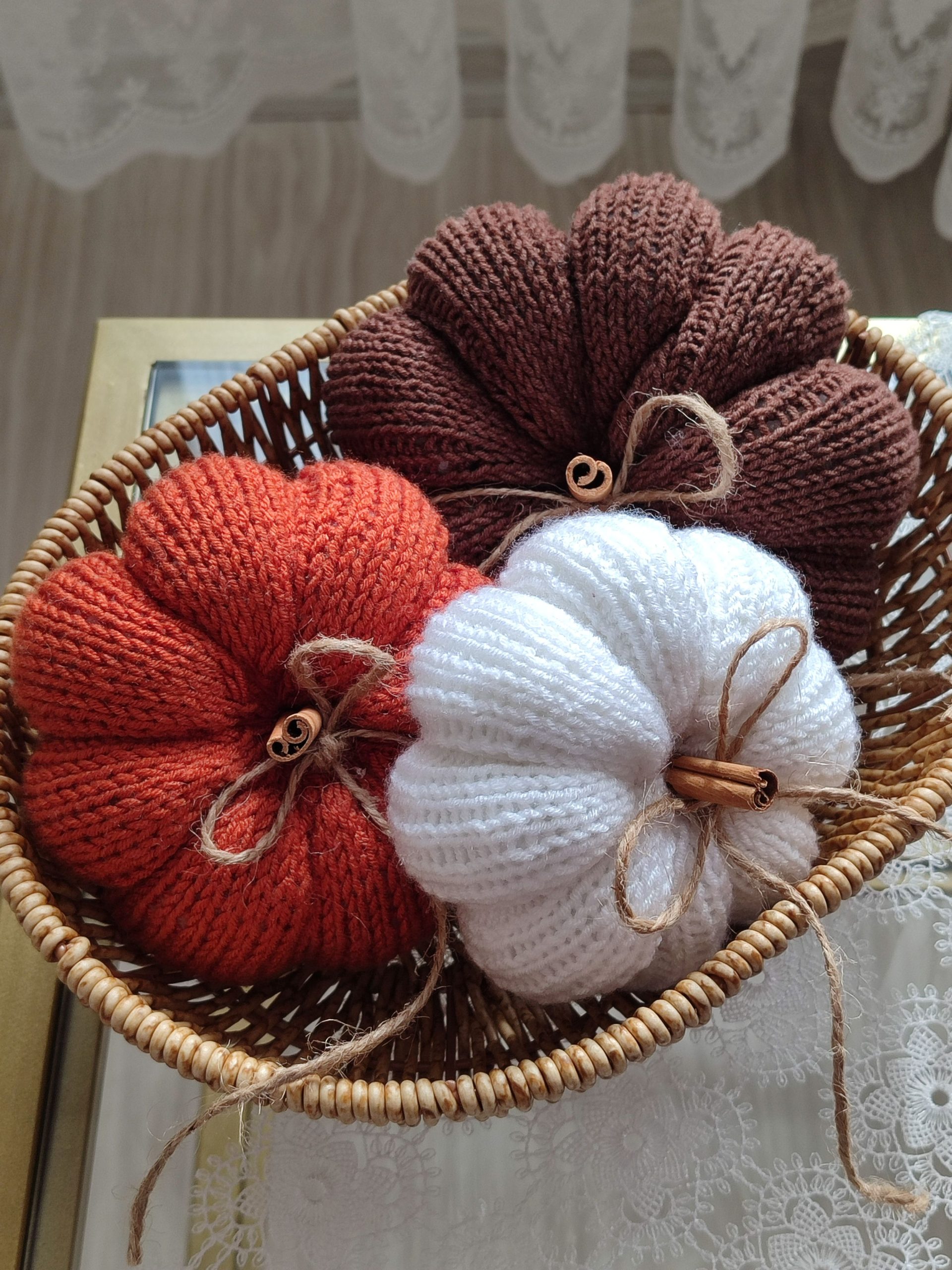 Cozy knitted pumpkins in earthy tones placed in a wicker basket, enhancing autumn home decor.