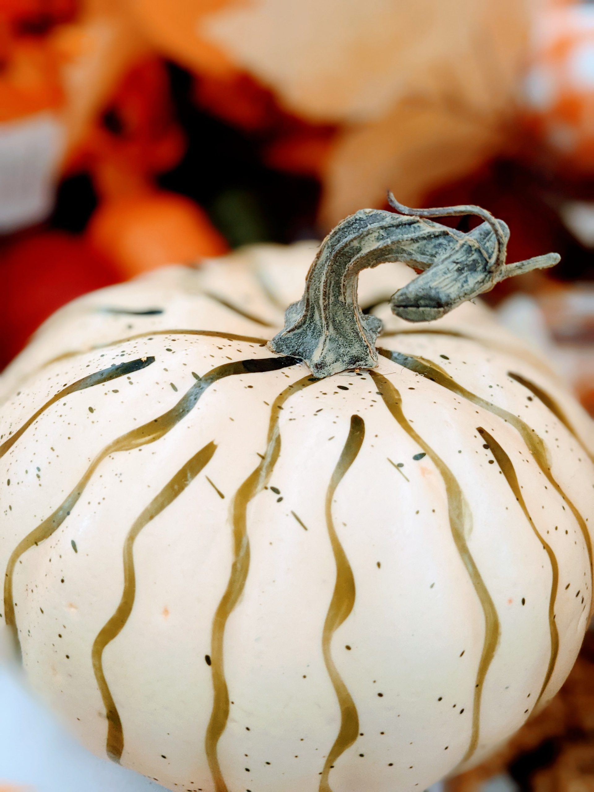Detailed shot of a white pumpkin with decorative paint patterns, evoking autumn themes.