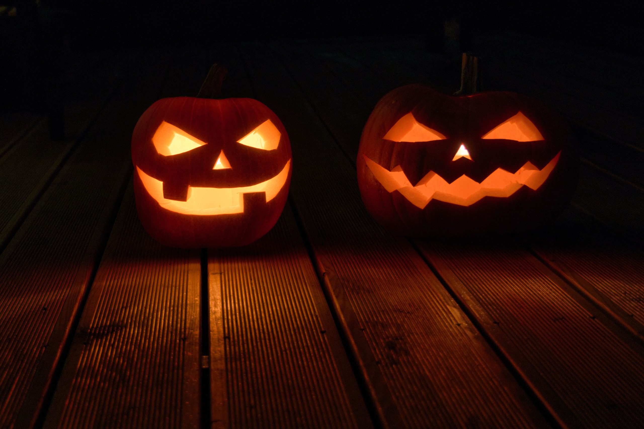 Eerie jack-o'-lanterns glowing on a wooden deck for a Halloween night.