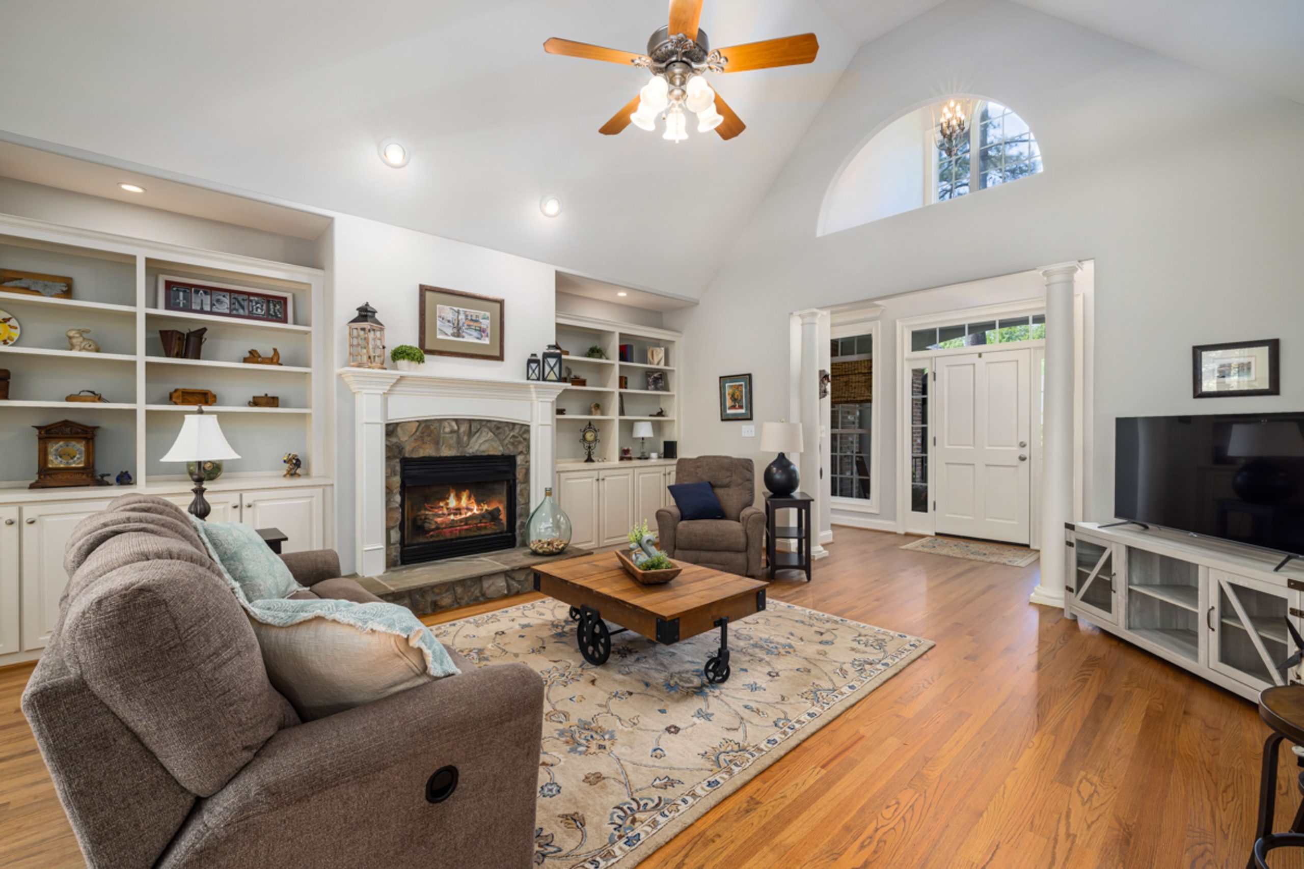 Elegant living room with fireplace, vaulted ceiling, and warm decor for a welcoming atmosphere.
