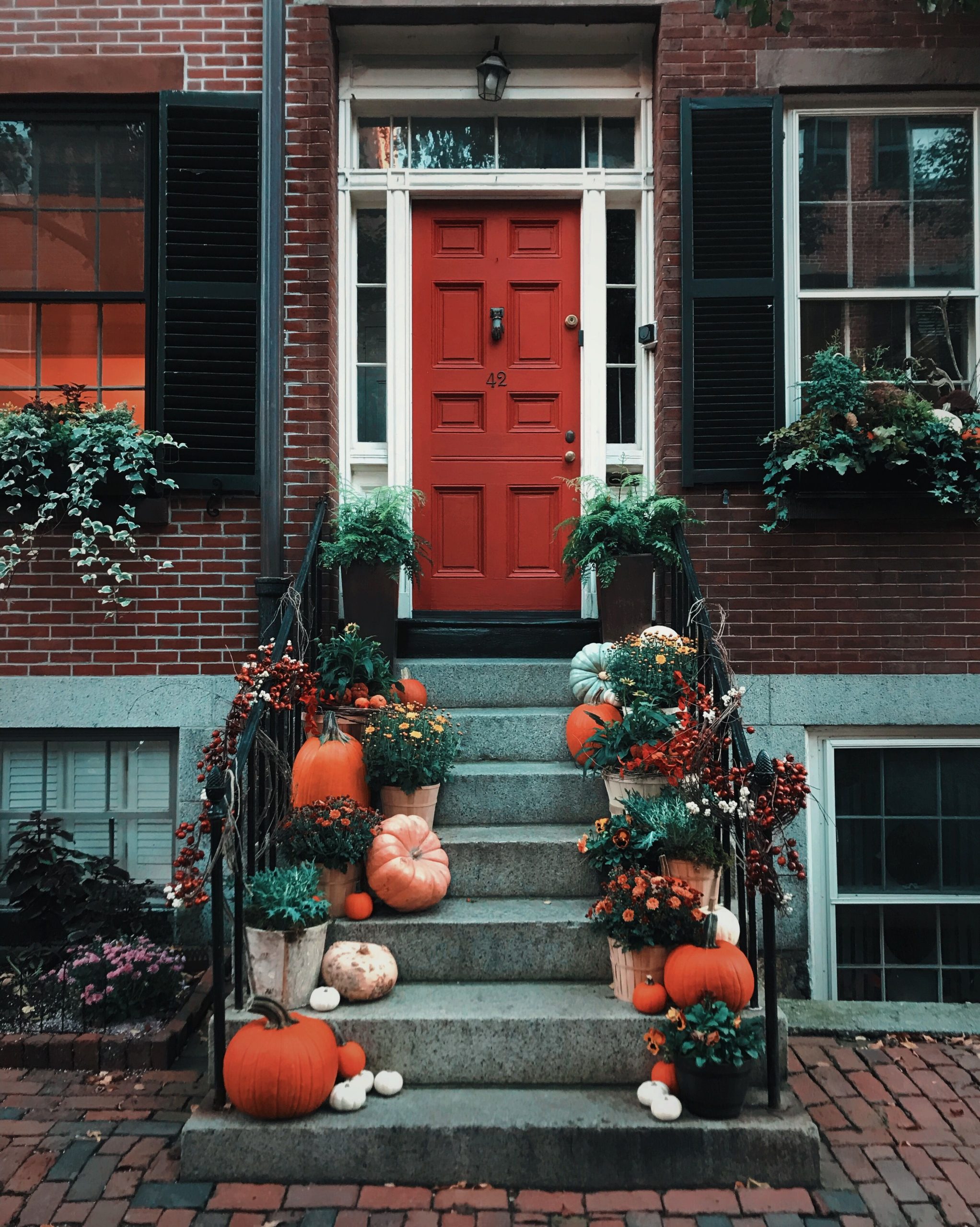 Festive autumn decorations with pumpkins and greenery on a Boston doorstep.
