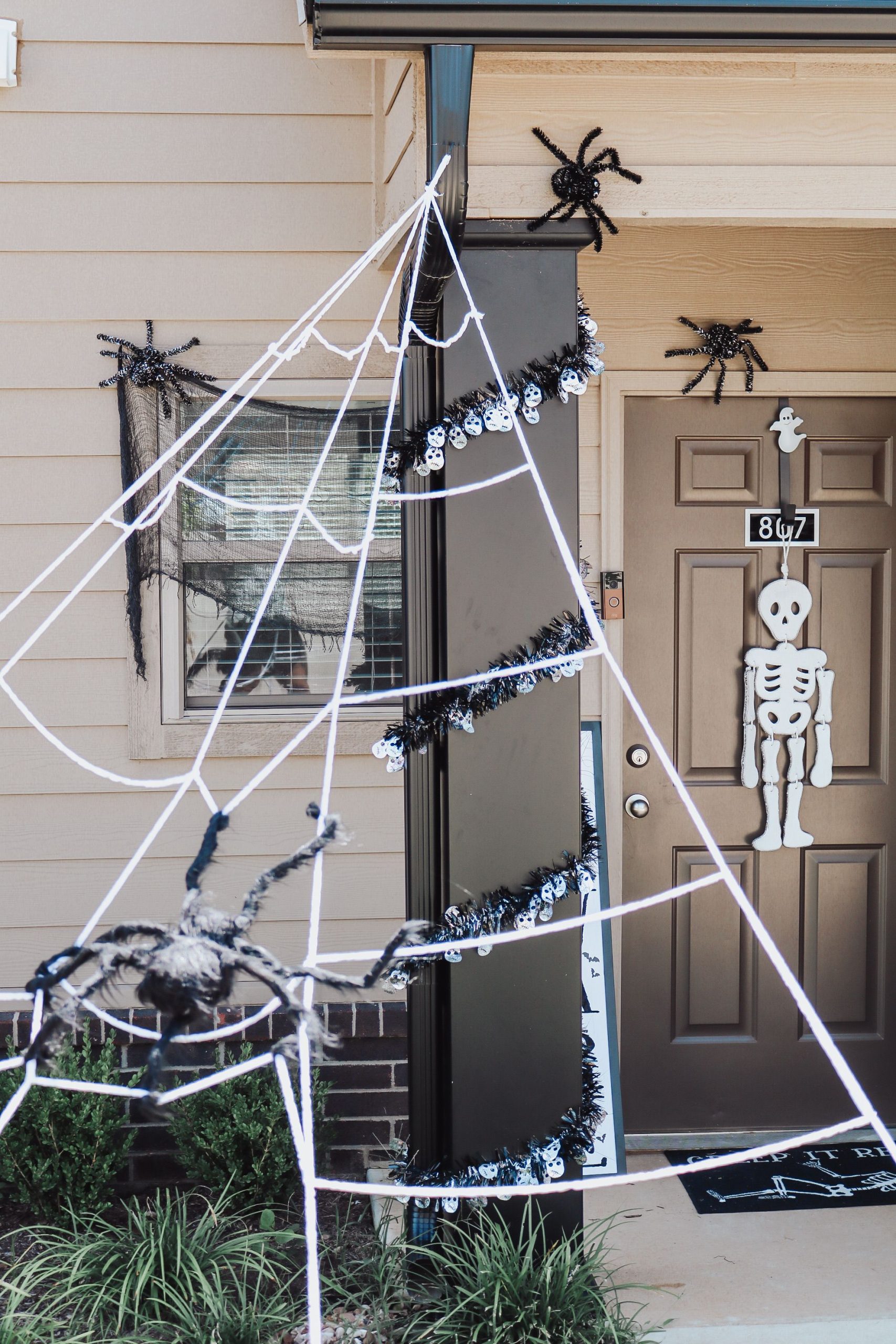 Festive Halloween porch setup with spider webs and a skeleton decoration.