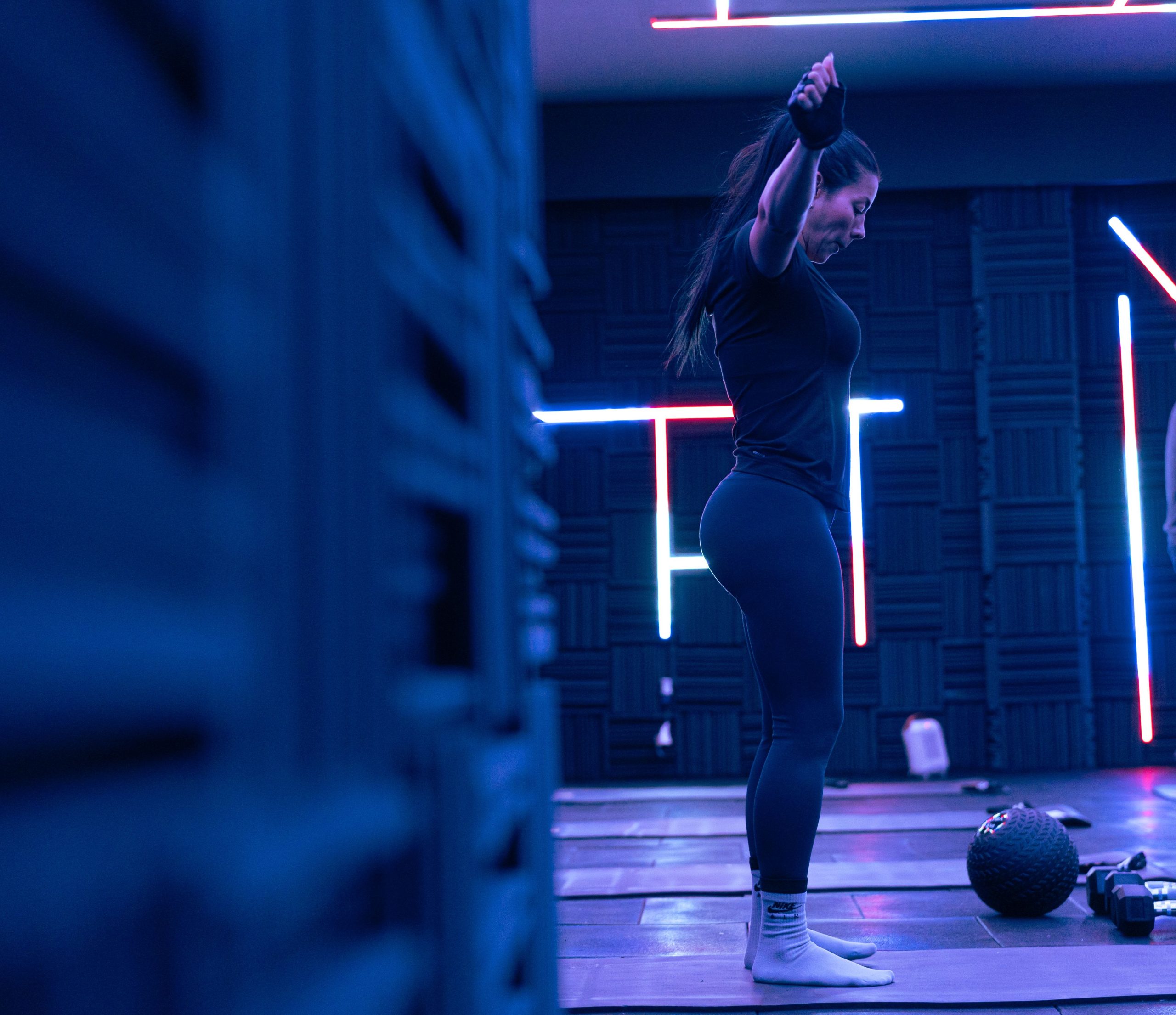 Fitness enthusiast exercising in a stylish neon-lit studio, embodying strength and focus.