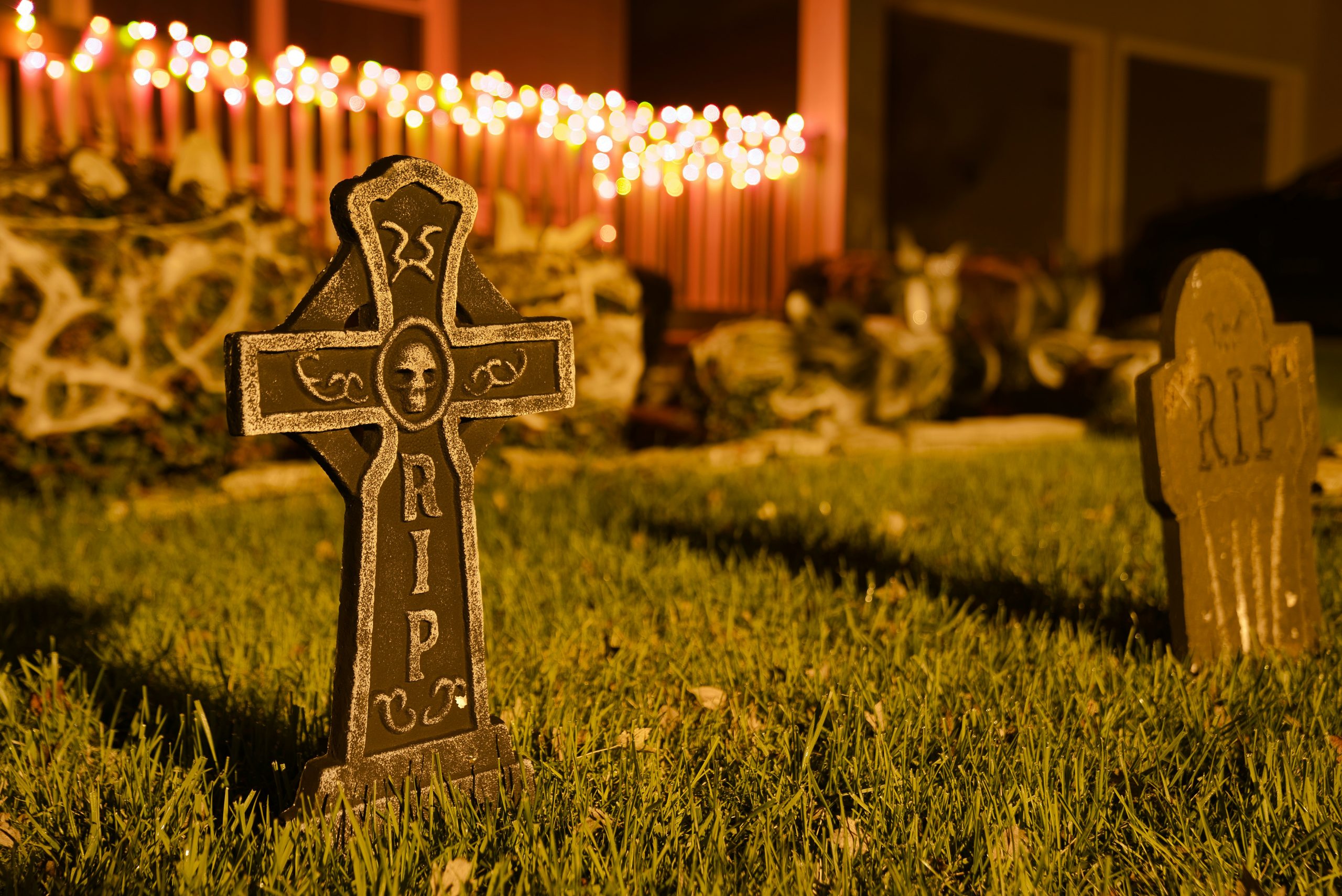 Front yard tombstones with lights in the background, decorations for Halloween