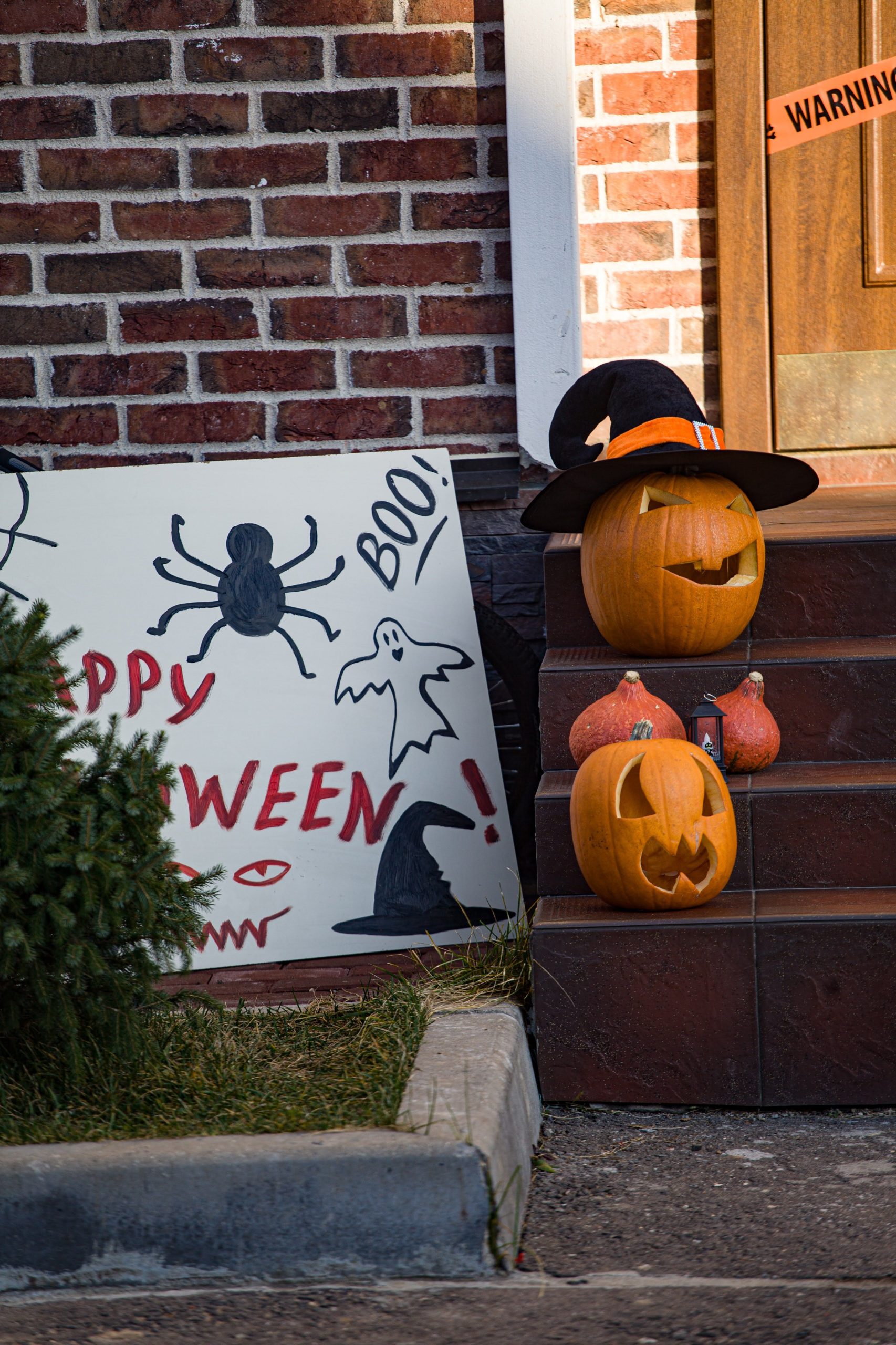 Halloween decorations featuring carved pumpkins and spooky hand-drawn sign on porch steps.