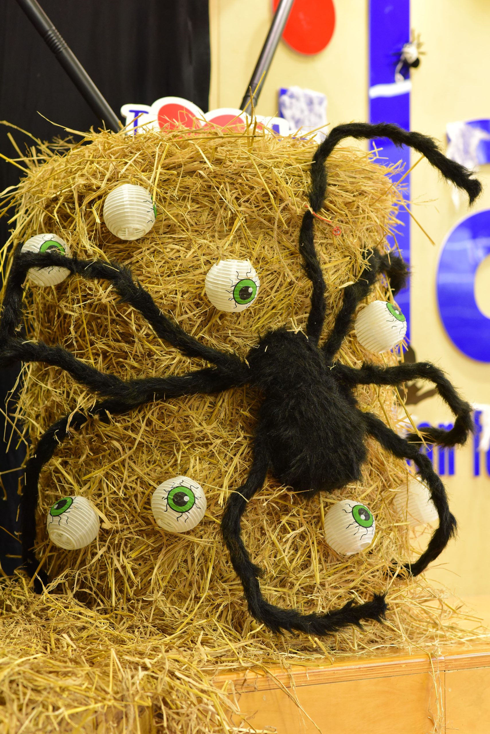 Halloween display featuring a giant spider on a hay bale with eyeball decorations.