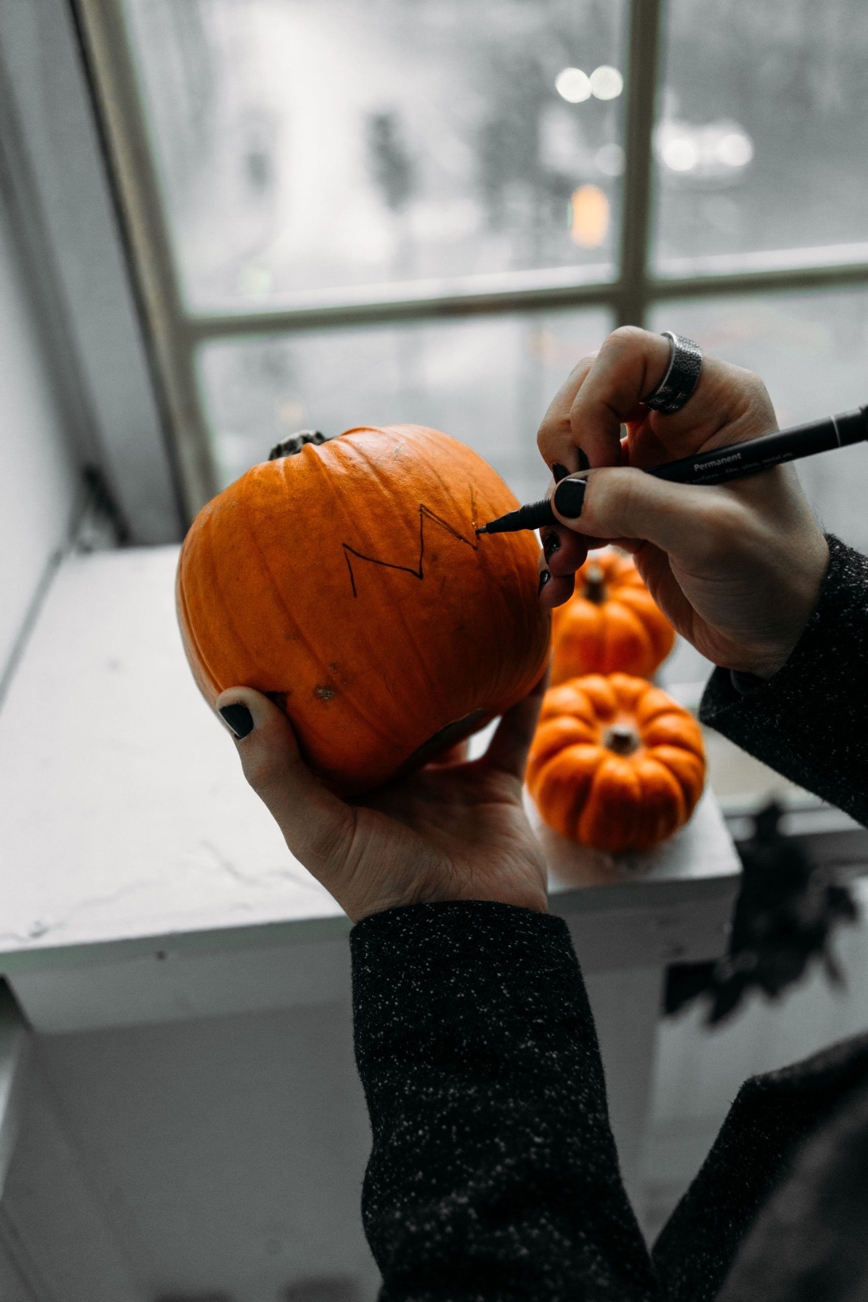 Hand drawing design on Halloween pumpkin indoors, perfect for spooky decoration ideas.