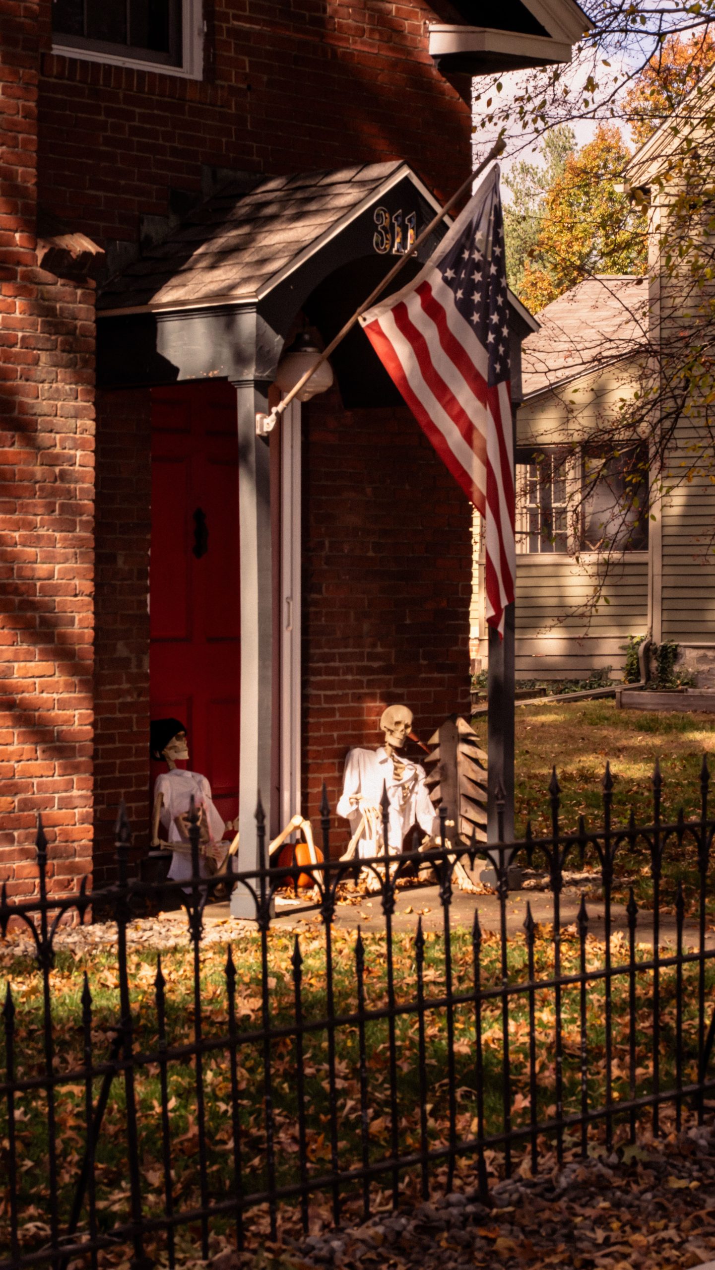 Historic American porch decorated with skeletons beside the US flag in autumn.