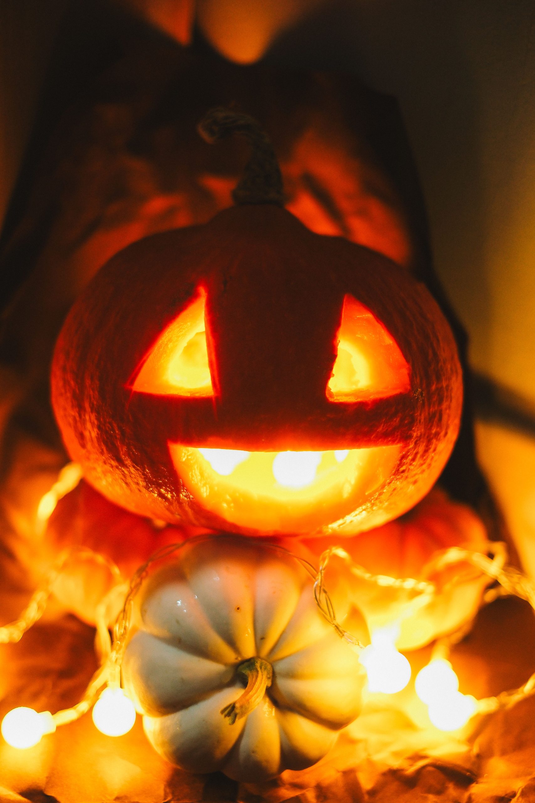 Illuminated carved pumpkin with candlelight and string lights, perfect for Halloween ambiance.