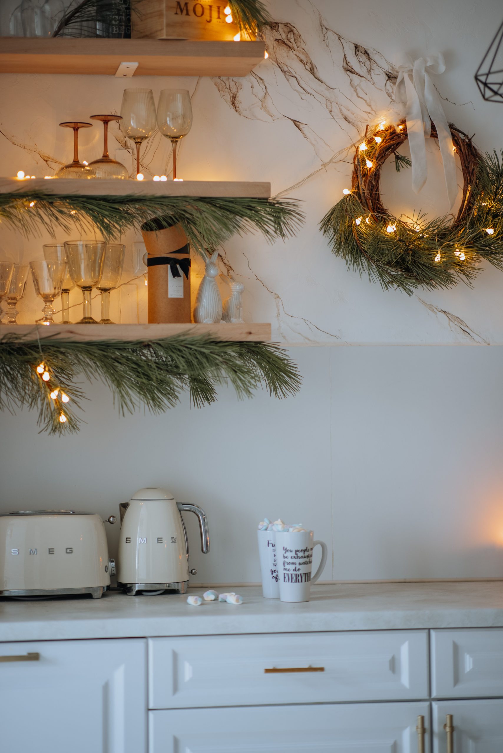 Modern kitchen with holiday decorations, lights, and stylish tableware, creating a warm festive atmosphere.