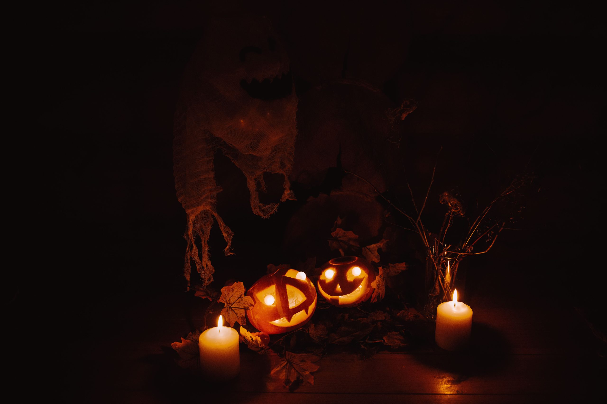 Moody Halloween display with glowing pumpkins and candles casting eerie shadows.