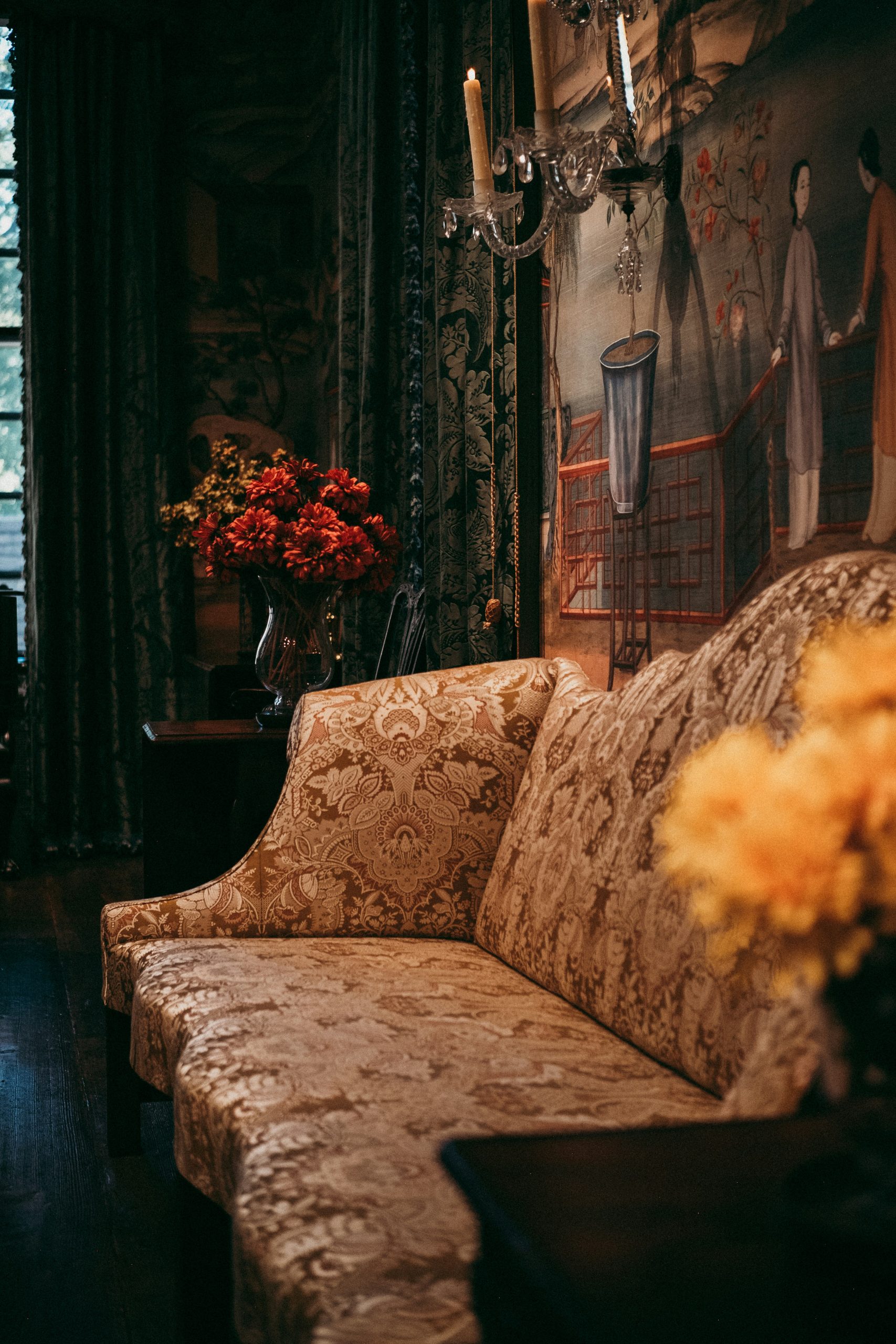 Ornate sofa with floral arrangements in dimly lit room