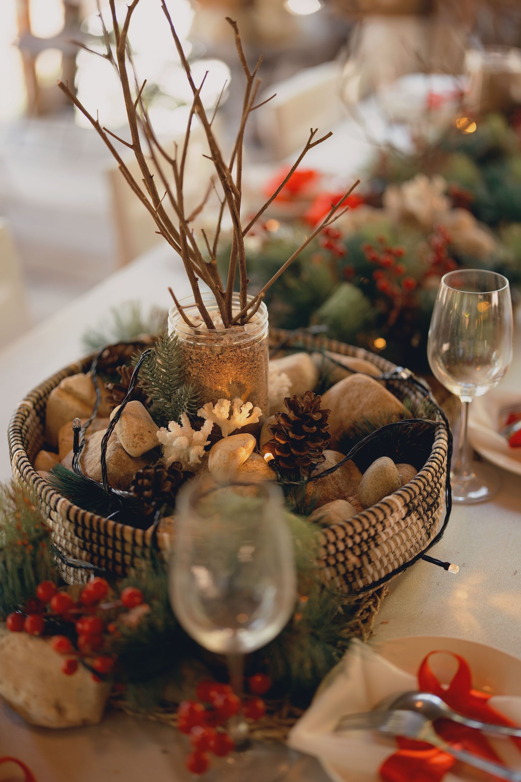 Rustic holiday table centerpiece with branches, pinecones, and berries, creating a warm festive atmosphere.