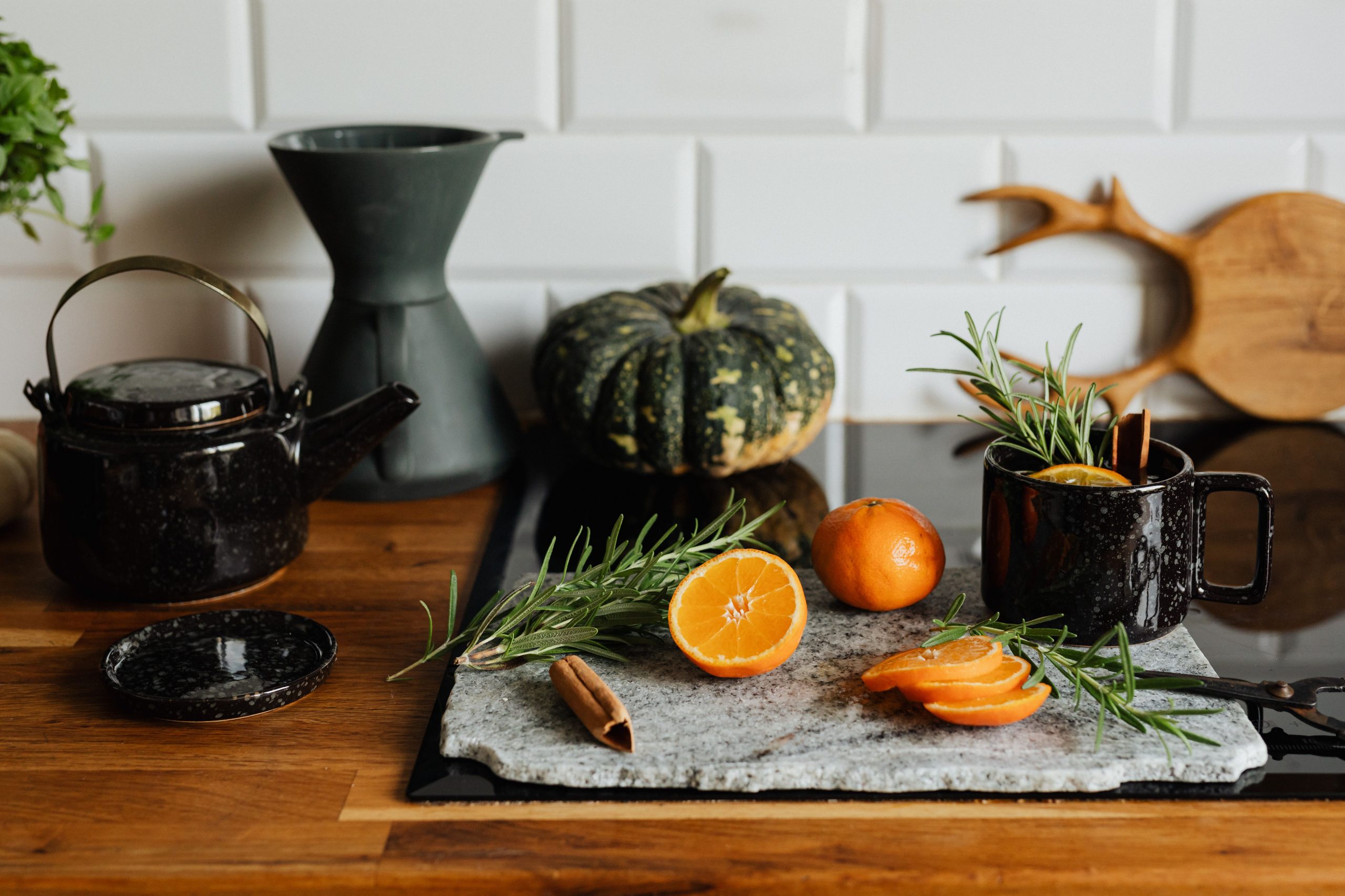 Rustic kitchen scene with sliced orange, herbs, and a cozy drink, perfect for autumn vibes.