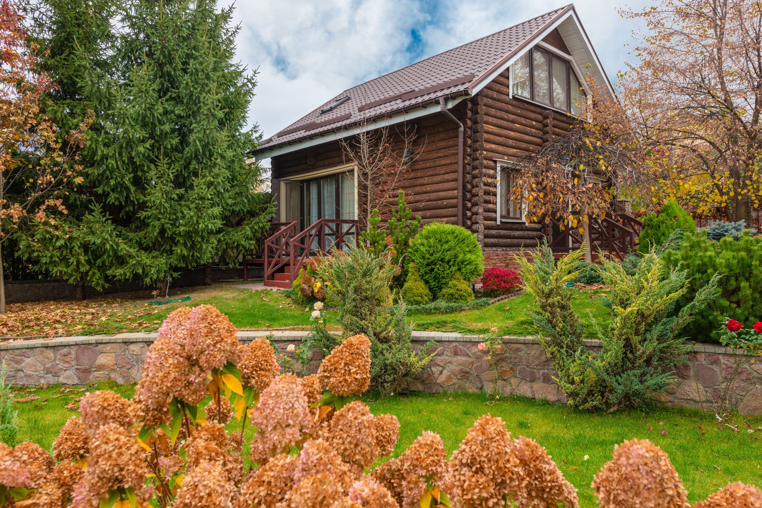 Rustic wooden cabin surrounded by vibrant autumn foliage and well-kept garden.
