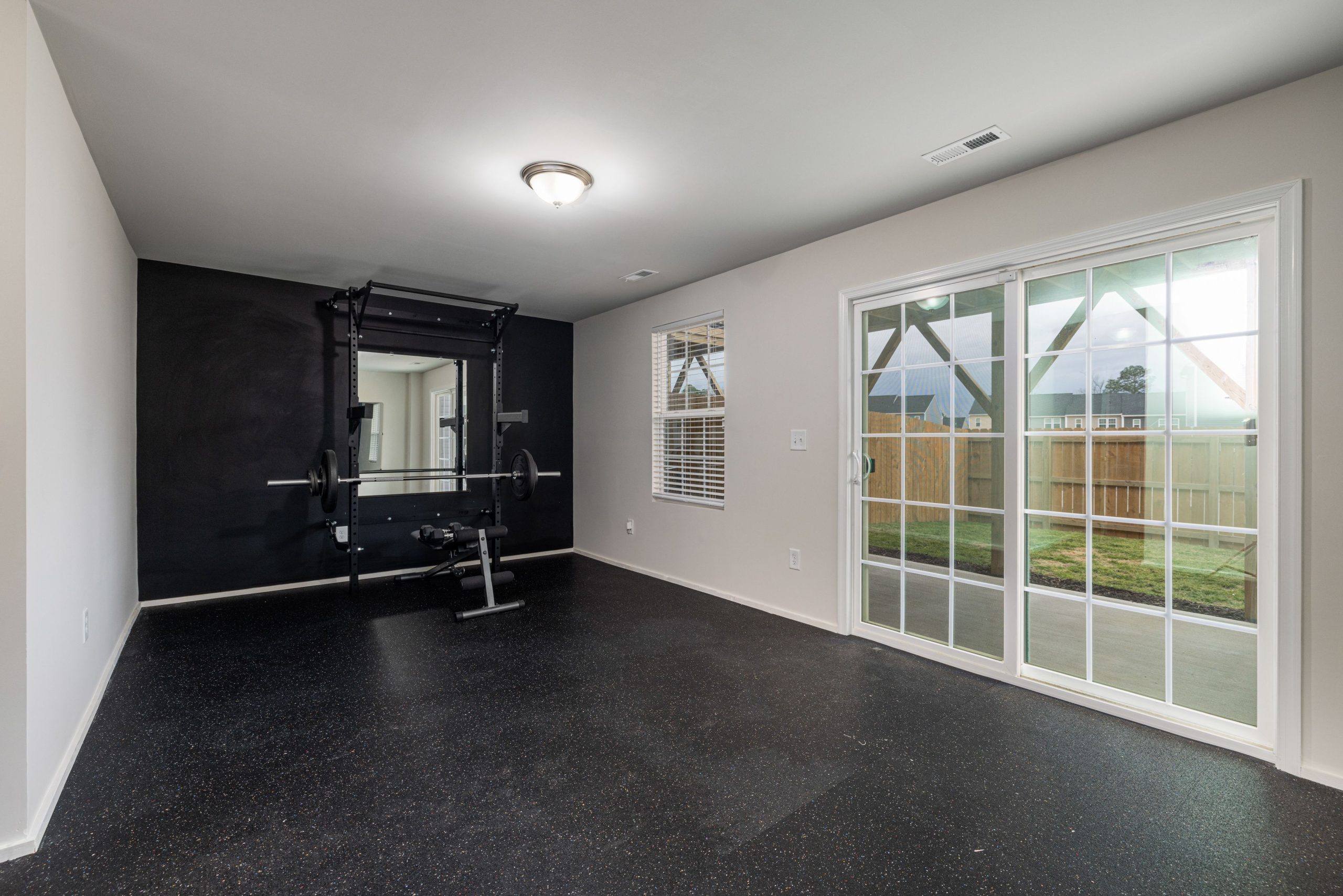 Spacious home gym featuring weightlifting equipment and a mirrored wall.