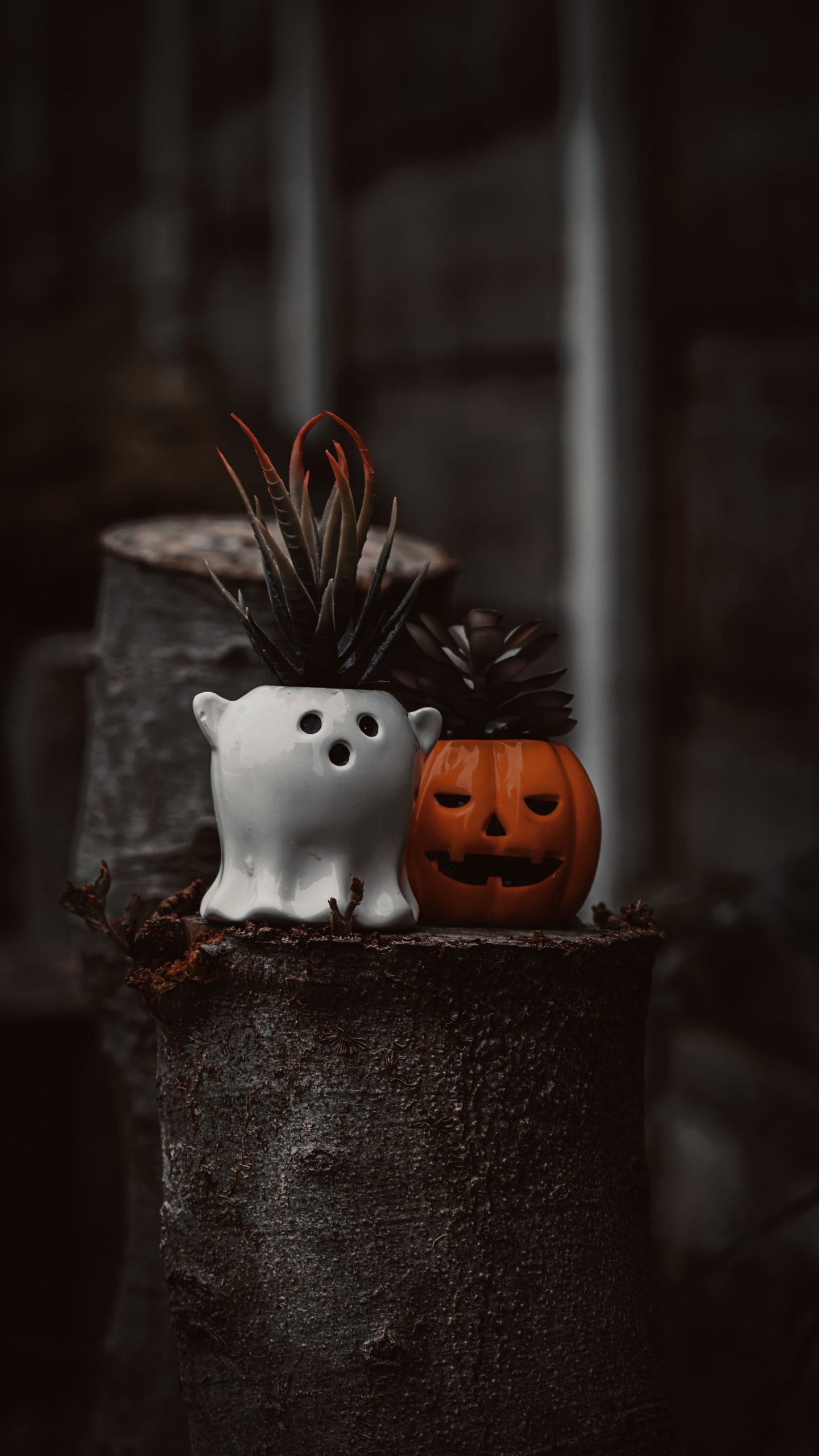 Spooky Halloween decor with ghost and pumpkin planters in a moody setting.