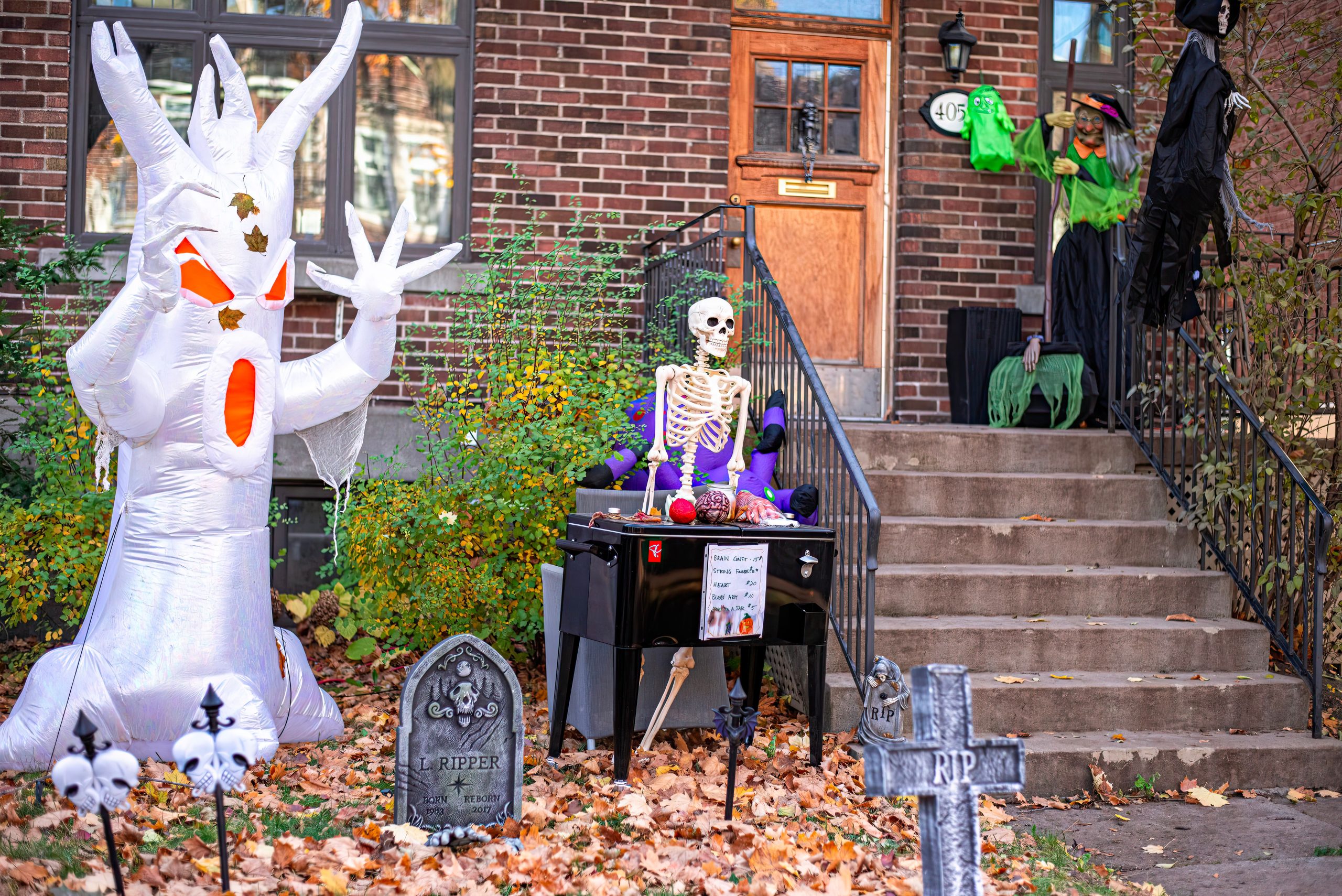 Spooky Halloween decorations featuring an inflatable ghost and skeleton on a porch.