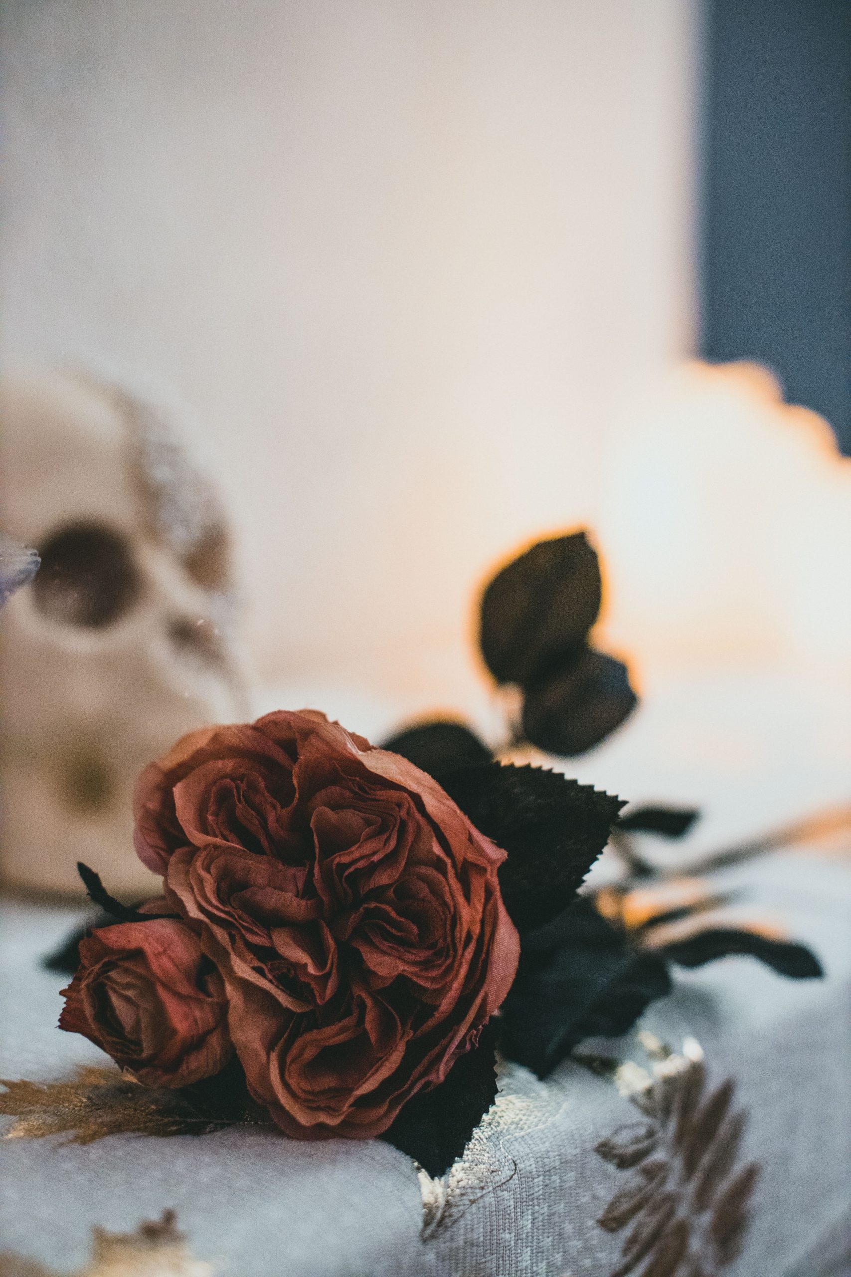 Spooky Halloween floral arrangement with roses and skull on a table, indoors.